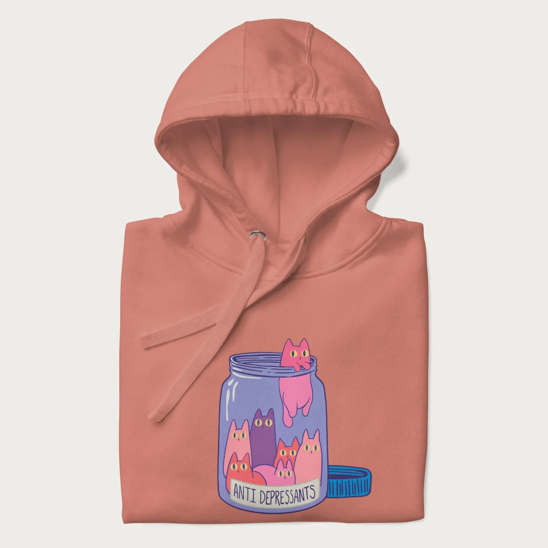 Cartoon cats in a clear jar labeled 'Anti Depressants' printed on a folded light pink hoodie.
