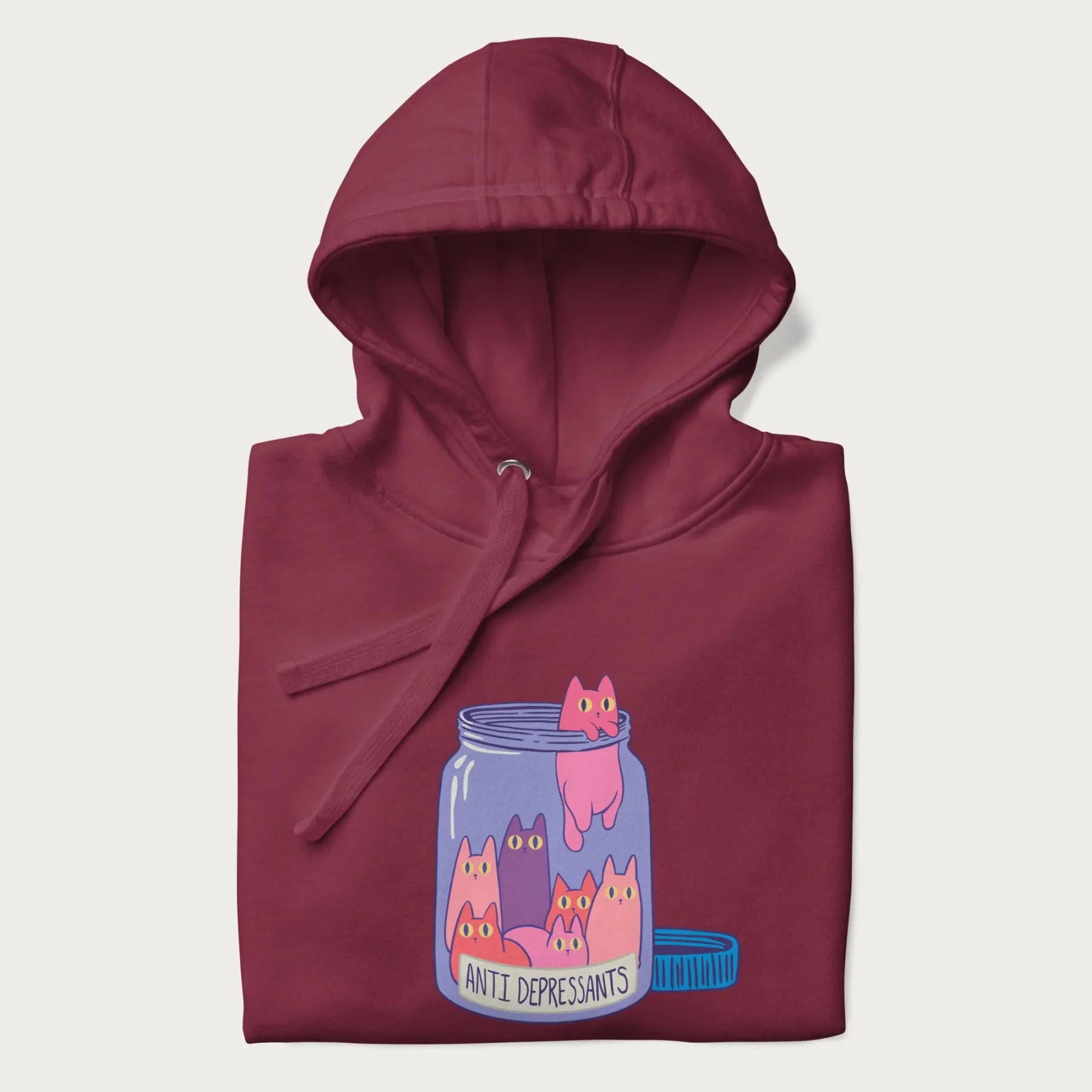 Cartoon cats in a clear jar labeled 'Anti Depressants' printed on a folded maroon hoodie.