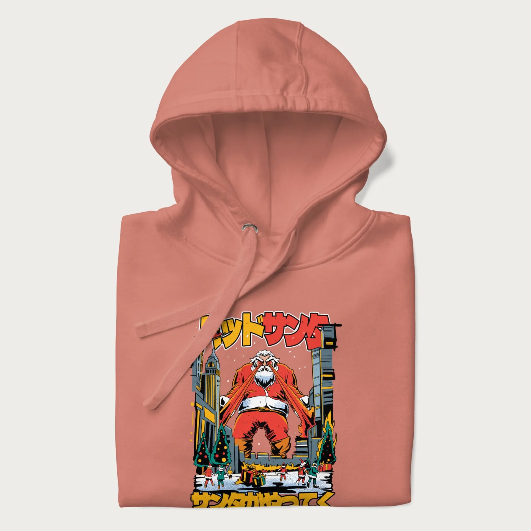 Folded light pink hoodie with Japanese graphic of Santa Claus with laser eyes attacking a festive city, with the Japanese text 'パッドサンタ' (Bad Santa).