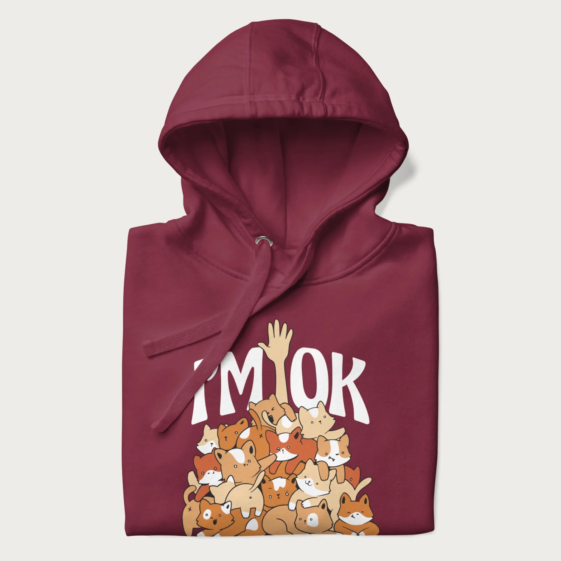 Folded maroon hoodie with a graphic of kittens piled on top of a person with "I'M OK" in large letters.