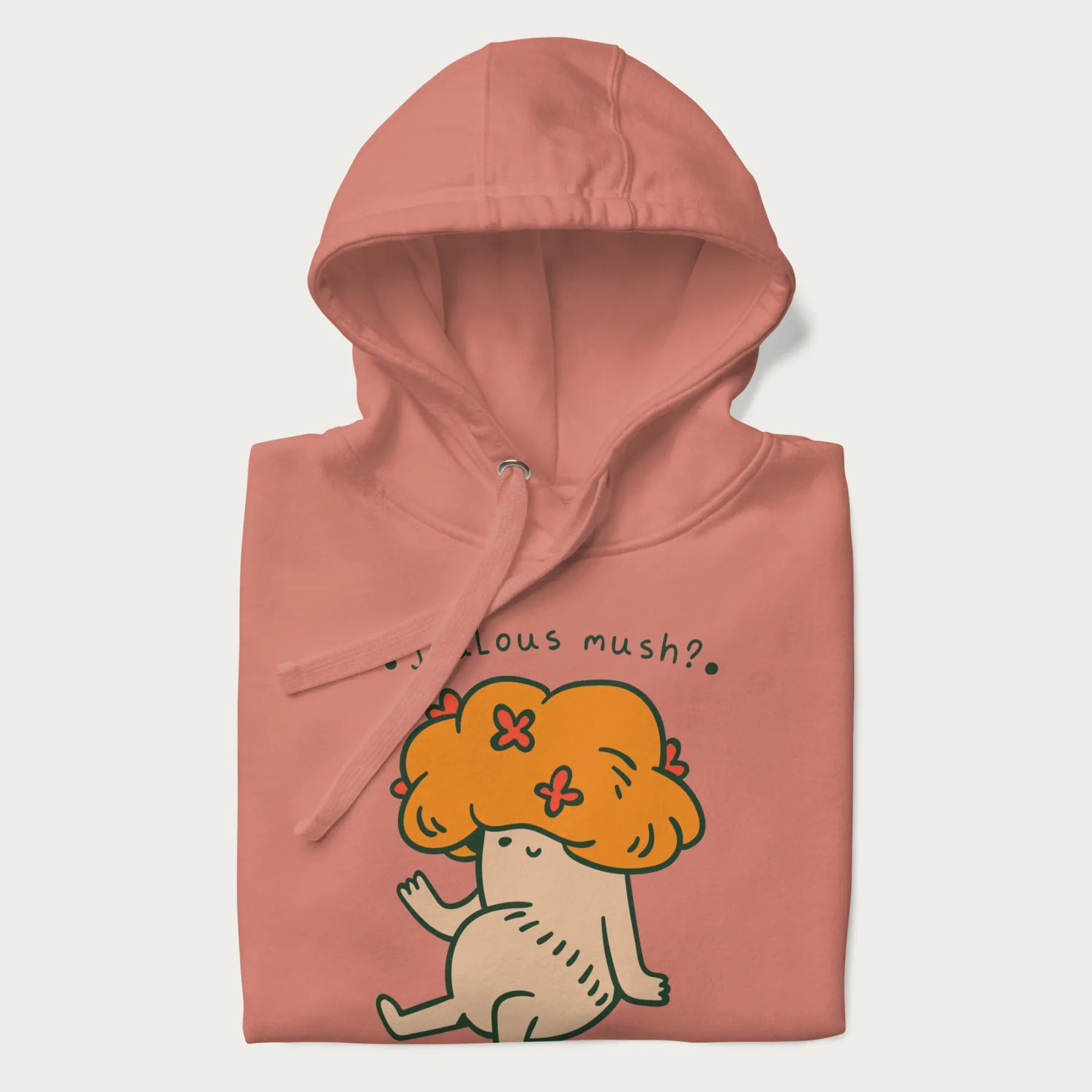 Folded light pink hoodie with a graphic of a mushroom character with an orange cap and the text 'Jealous mush?'.