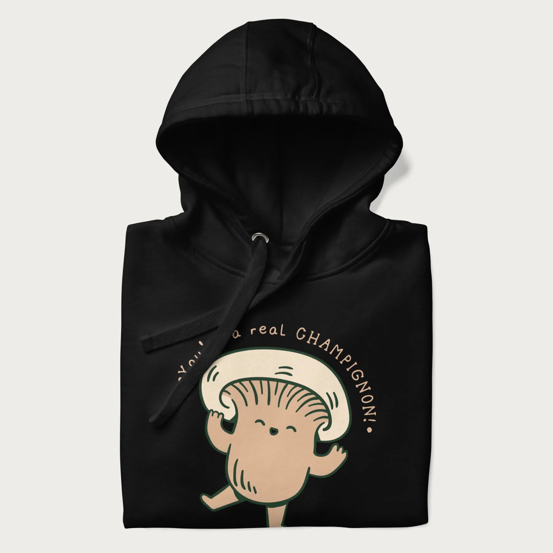 Folded black hoodie with a graphic of an adorable mushroom character and the text 'You're a real CHAMPIGNON!'.