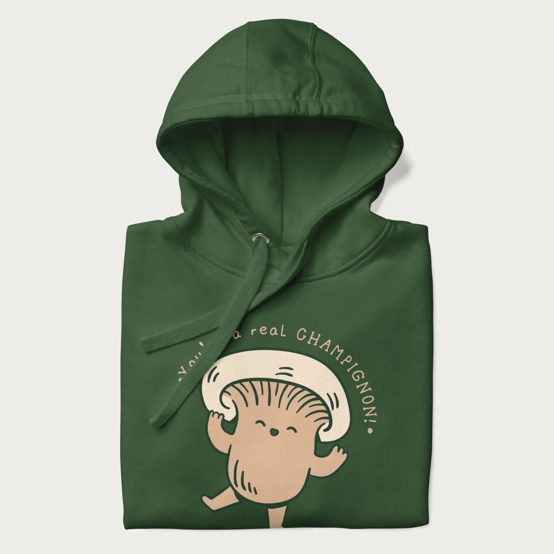 Folded forest green hoodie with a graphic of an adorable mushroom character and the text 'You're a real CHAMPIGNON!'.