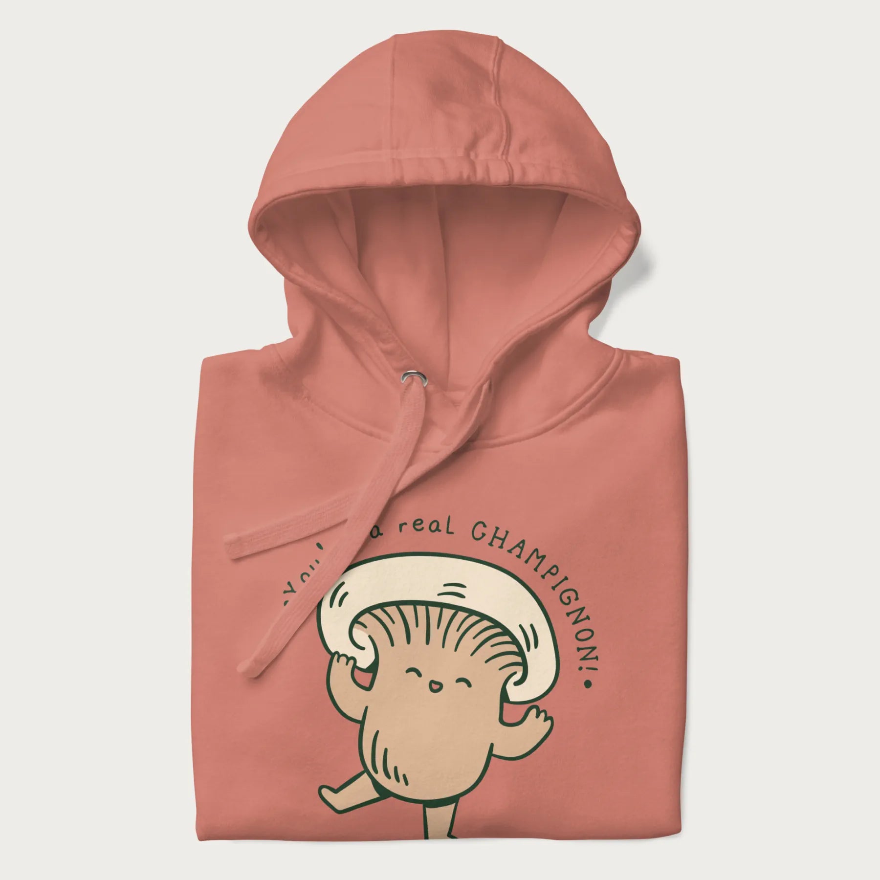 Folded light pink hoodie with a graphic of an adorable mushroom character and the text 'You're a real CHAMPIGNON!'.