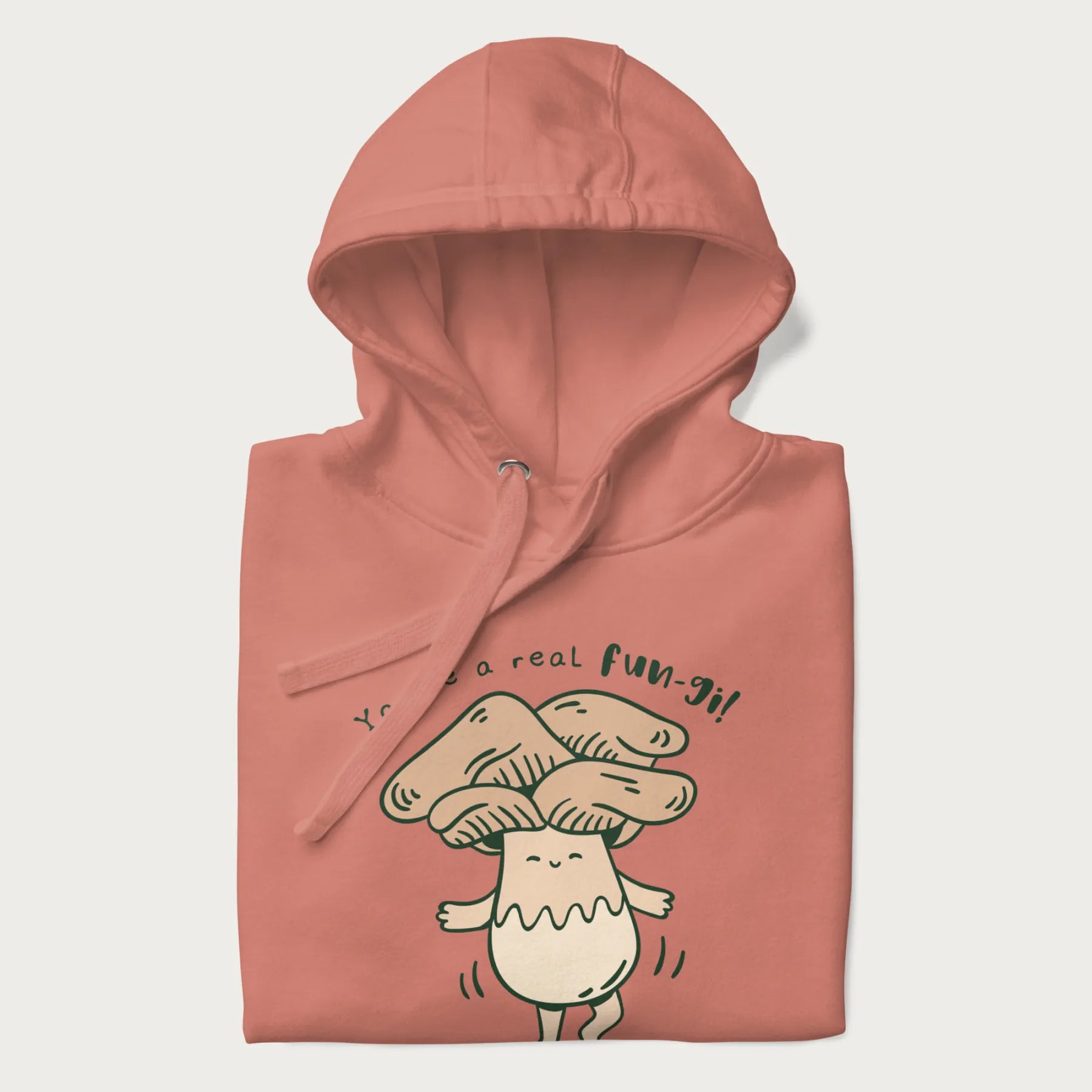 Folded light pink hoodie with a graphic of a happy mushroom character and the text 'You're a real fun-gi!'.