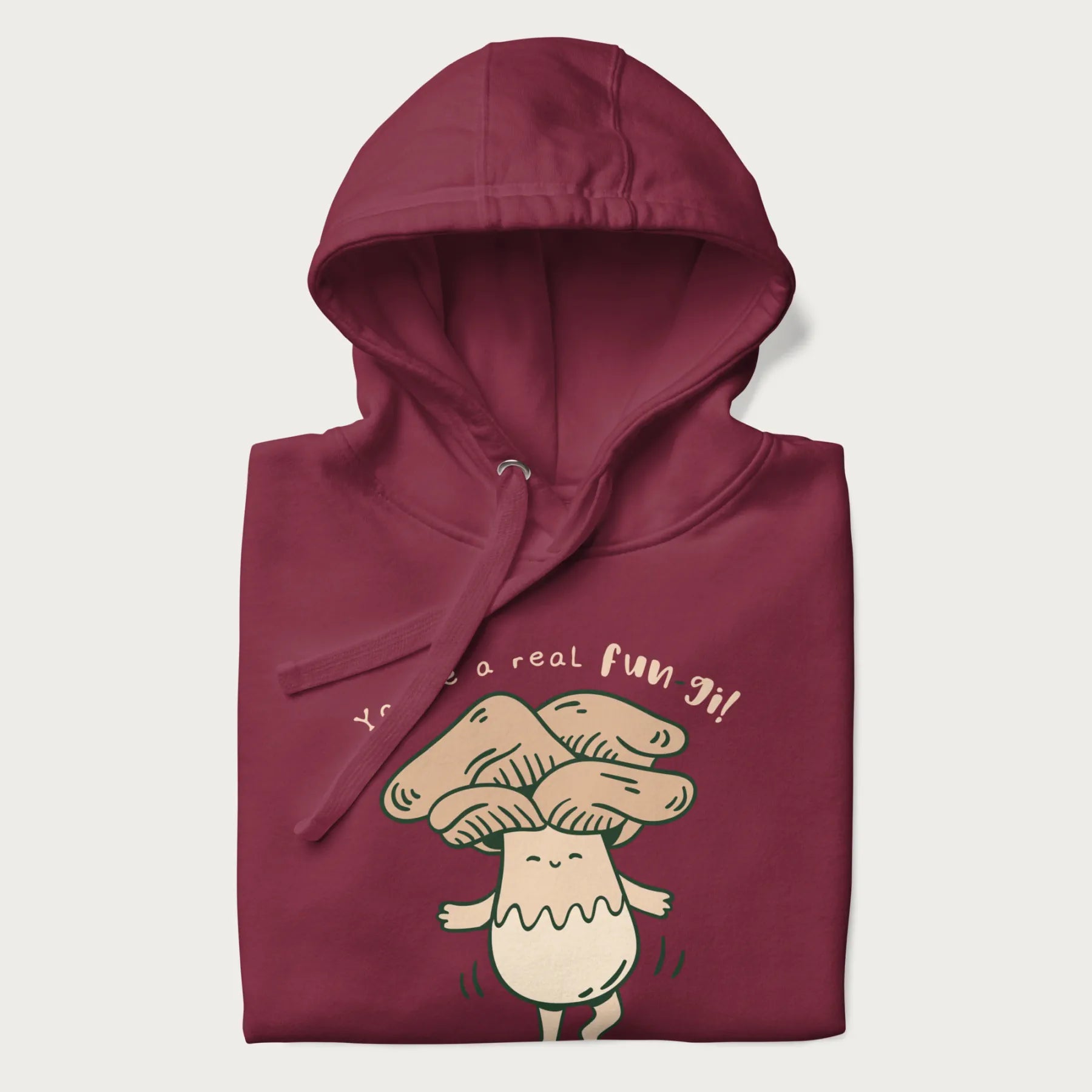 Folded maroon hoodie with a graphic of a happy mushroom character and the text 'You're a real fun-gi!'.