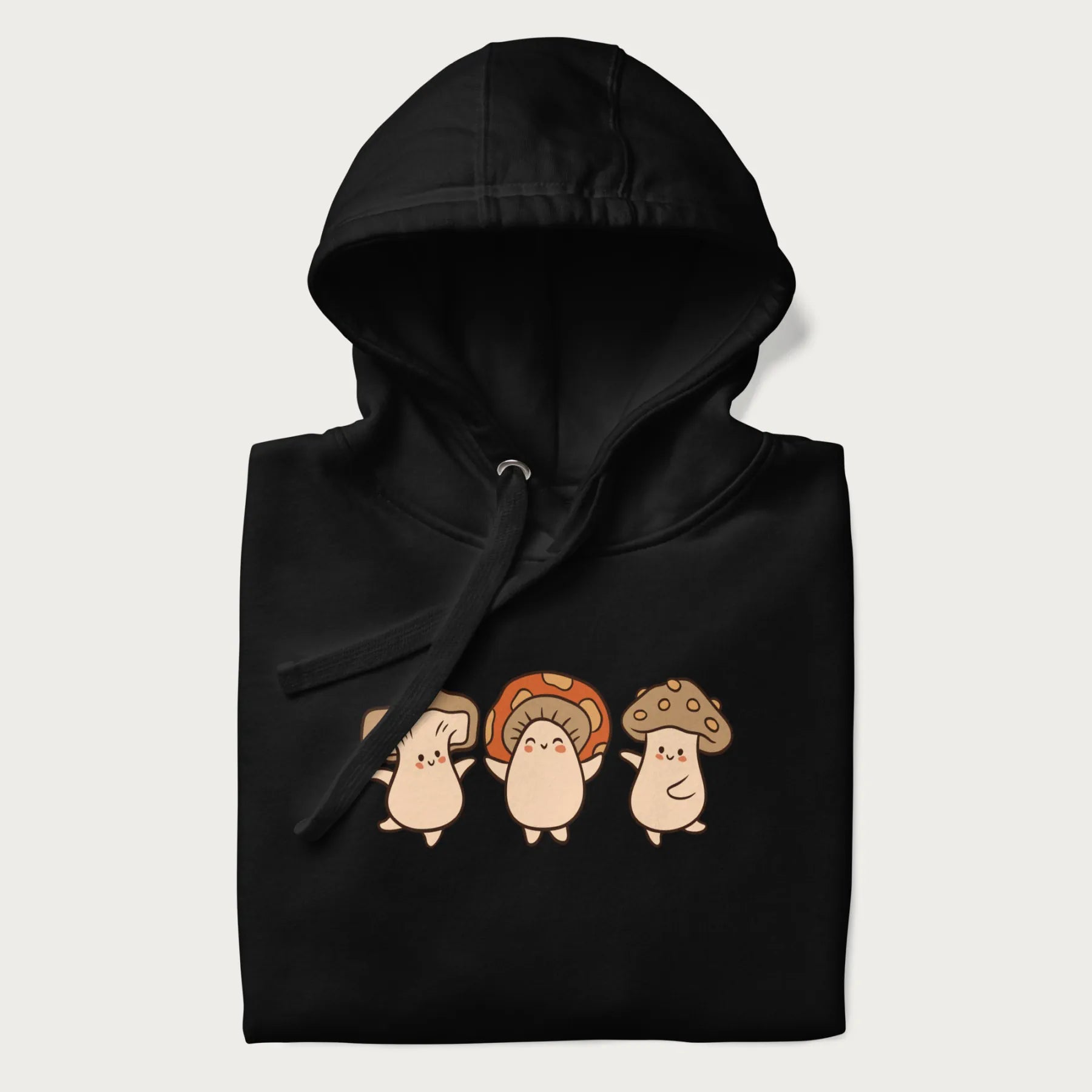 Folded black hoodie with a graphic illustration of three cheerful dancing mushrooms.