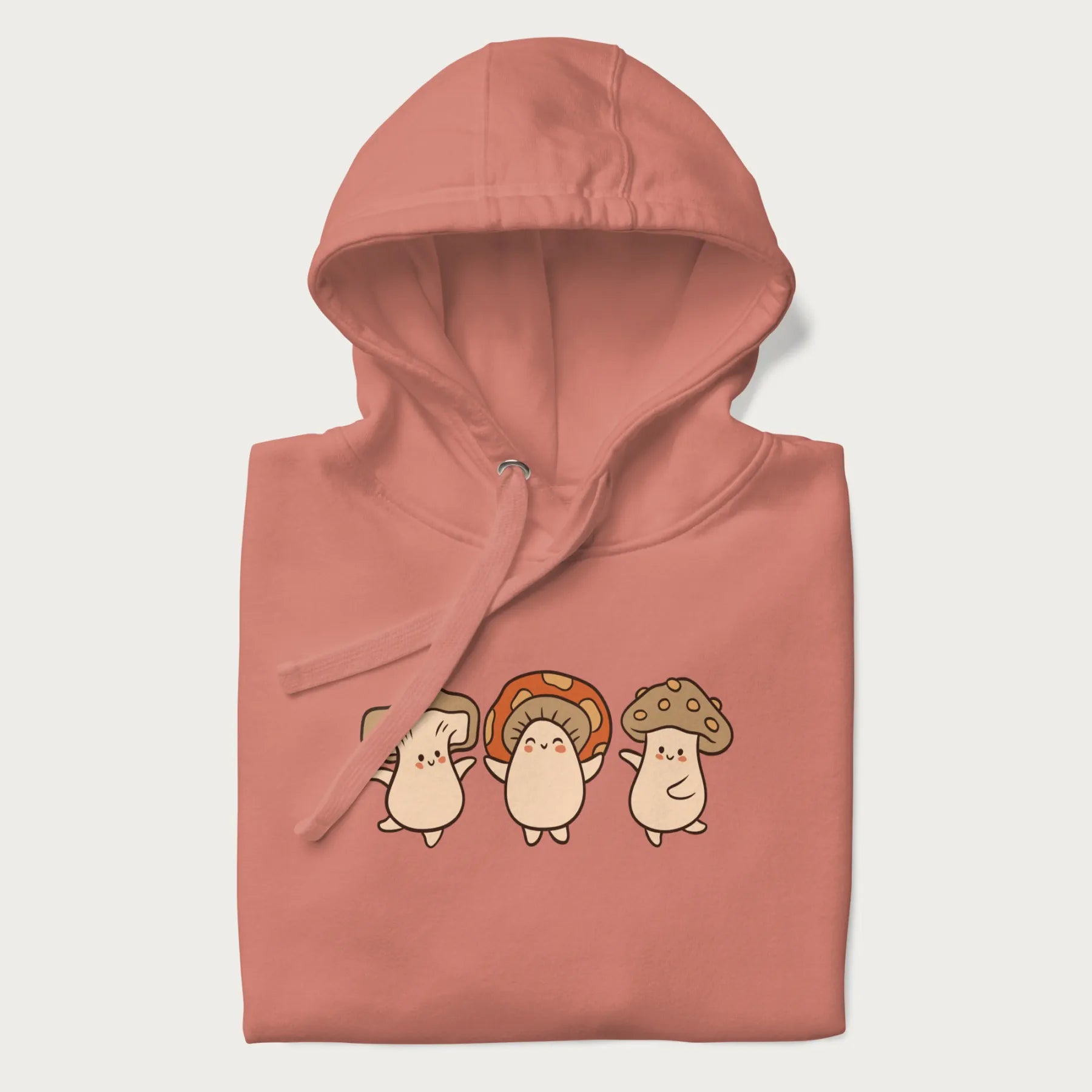 Folded light pink hoodie with a graphic illustration of three cheerful dancing mushrooms.