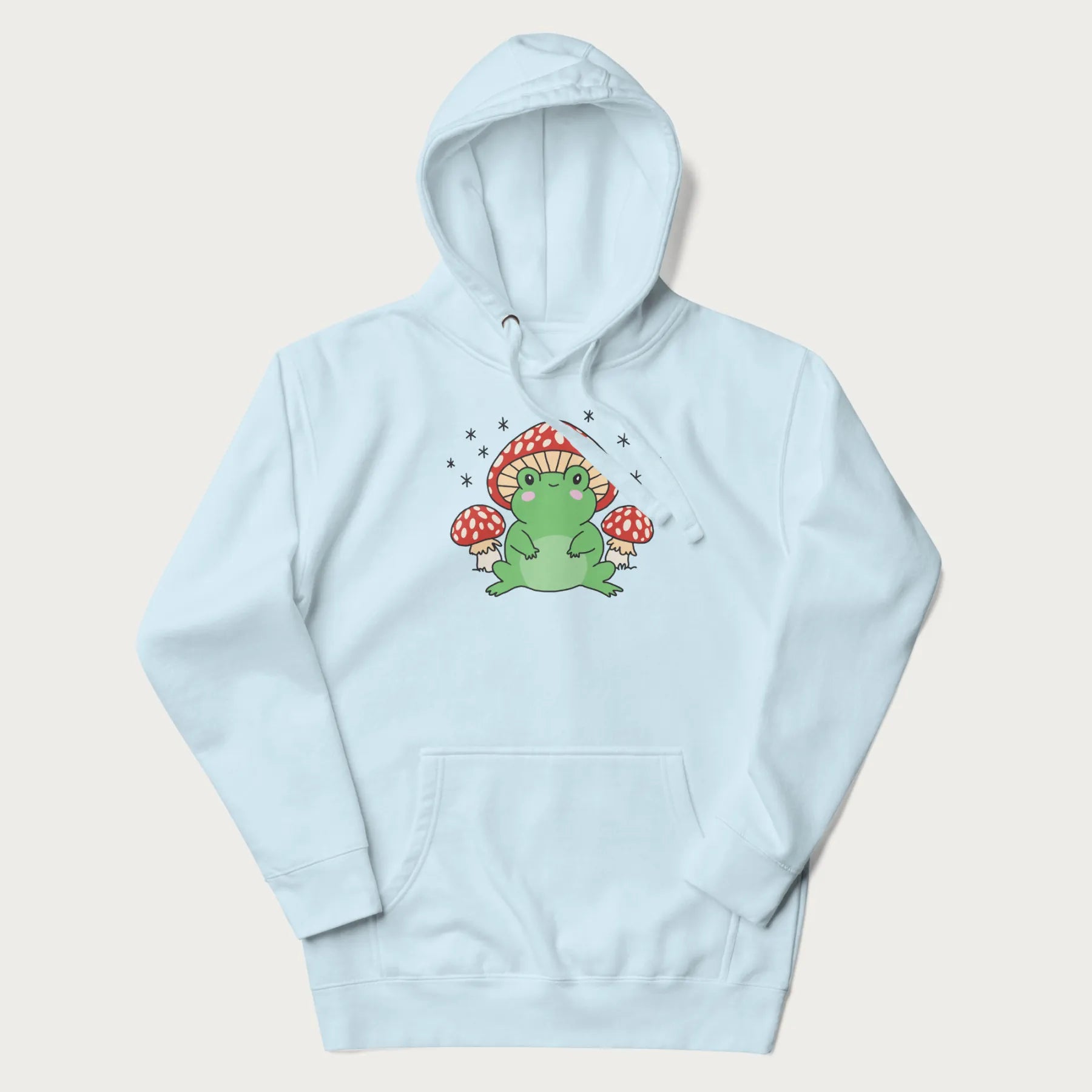 Folded light blue hoodie will illustration of a cute green frog with red and white mushrooms.