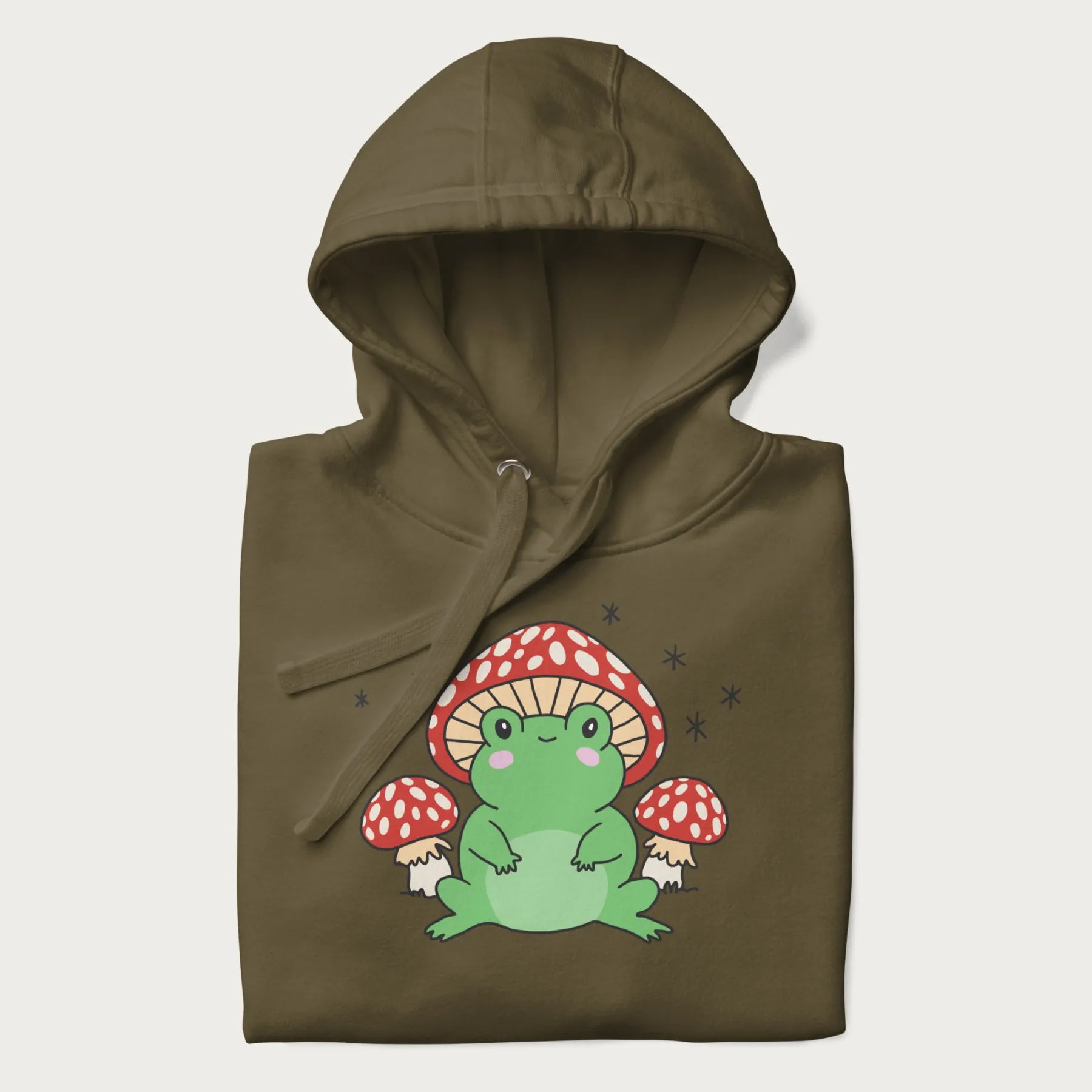 Folded military green hoodie will illustration of a cute green frog with red and white mushrooms.