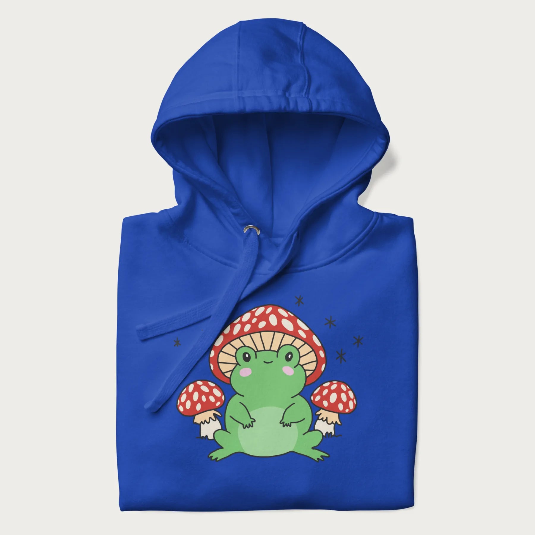 Folded royal blue hoodie will illustration of a cute green frog with red and white mushrooms.