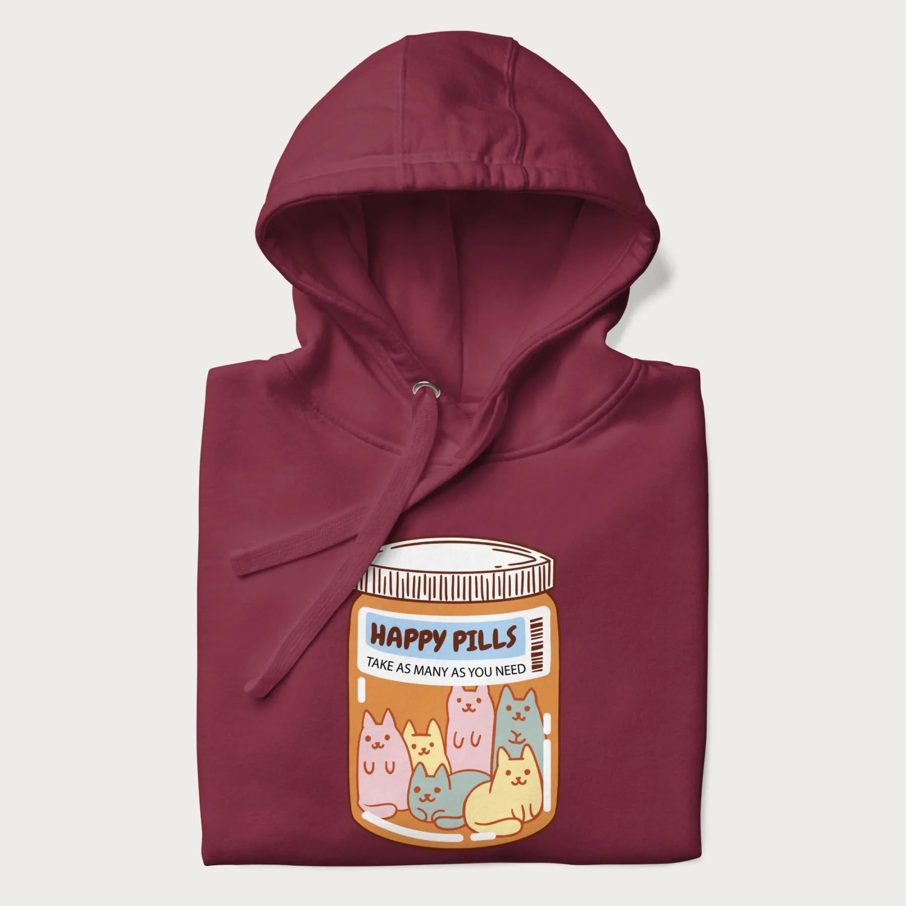 Cartoon cats in a pill bottle labeled 'Happy Pills' on a folded maroon hoodie.