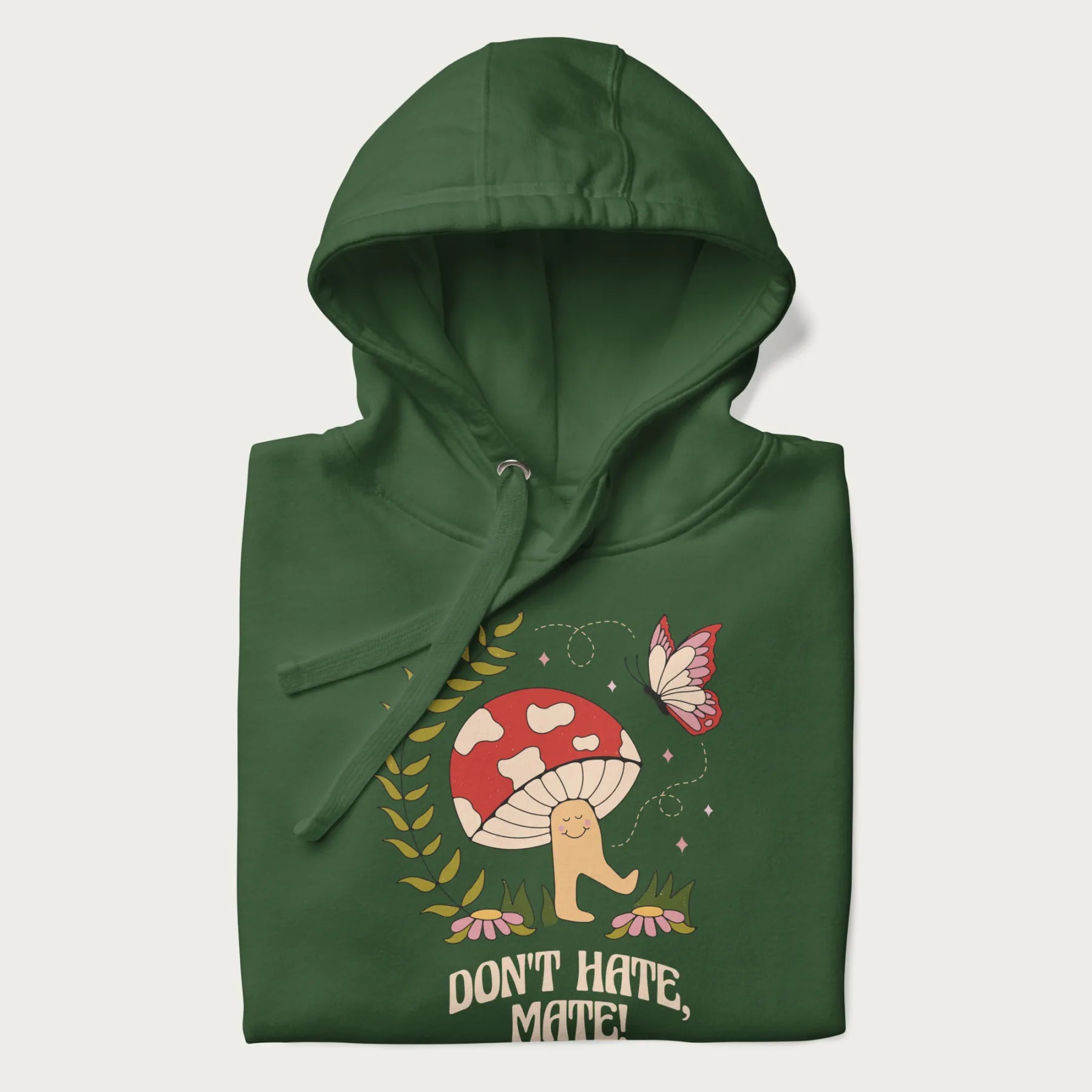 Folded forest green hoodie featuring a cute mushroom graphic with the text "Don't Hate, Mate."