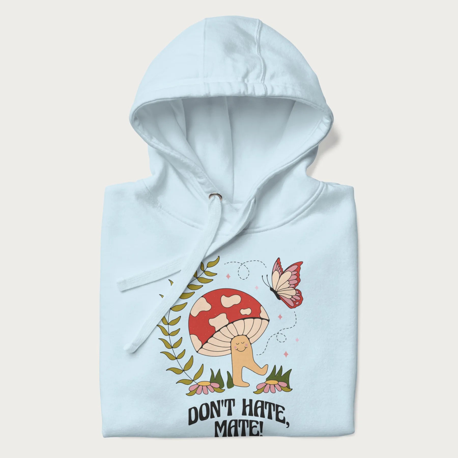 Folded light blue hoodie featuring a cute mushroom graphic with the text "Don't Hate, Mate."