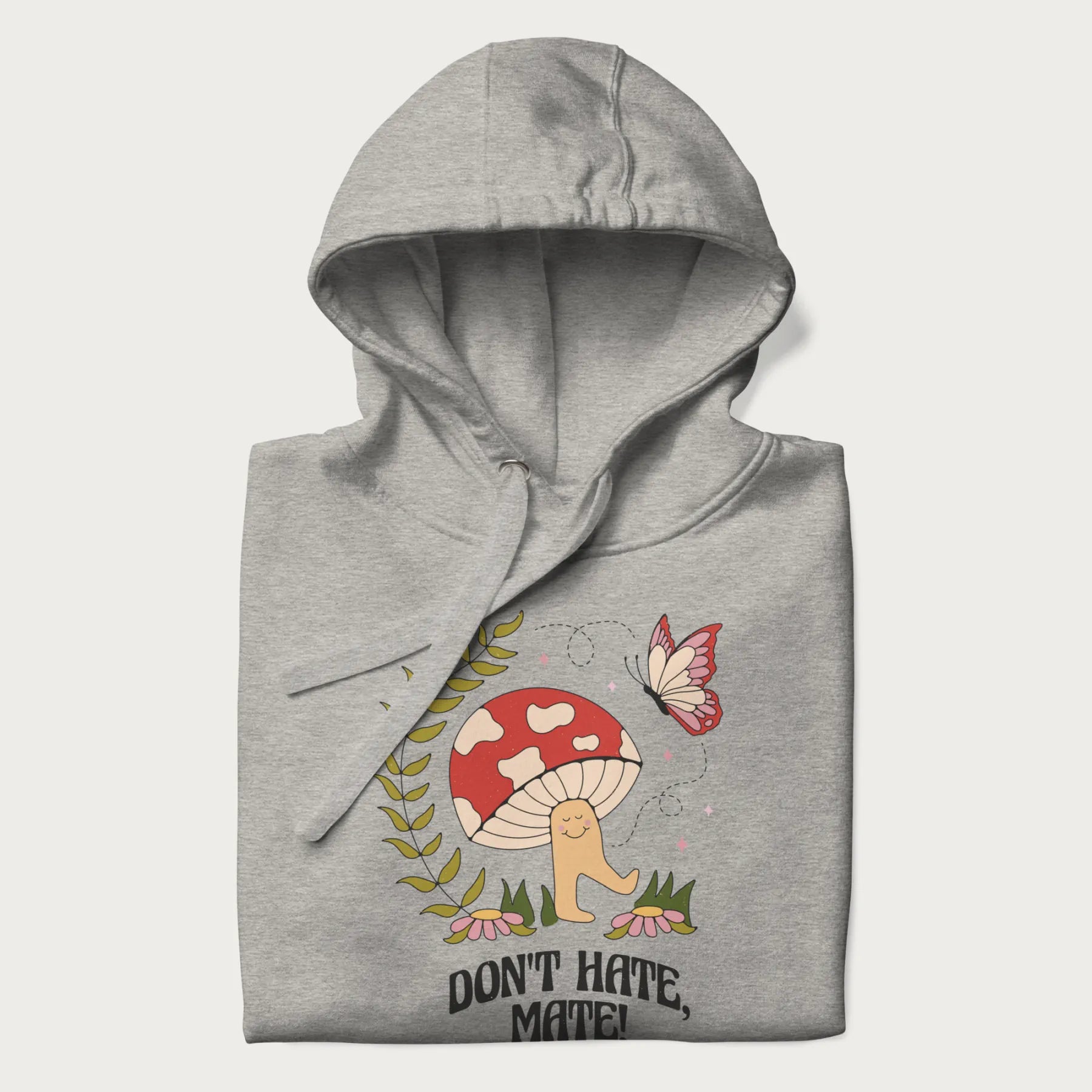 Folded light grey hoodie featuring a cute mushroom graphic with the text "Don't Hate, Mate."
