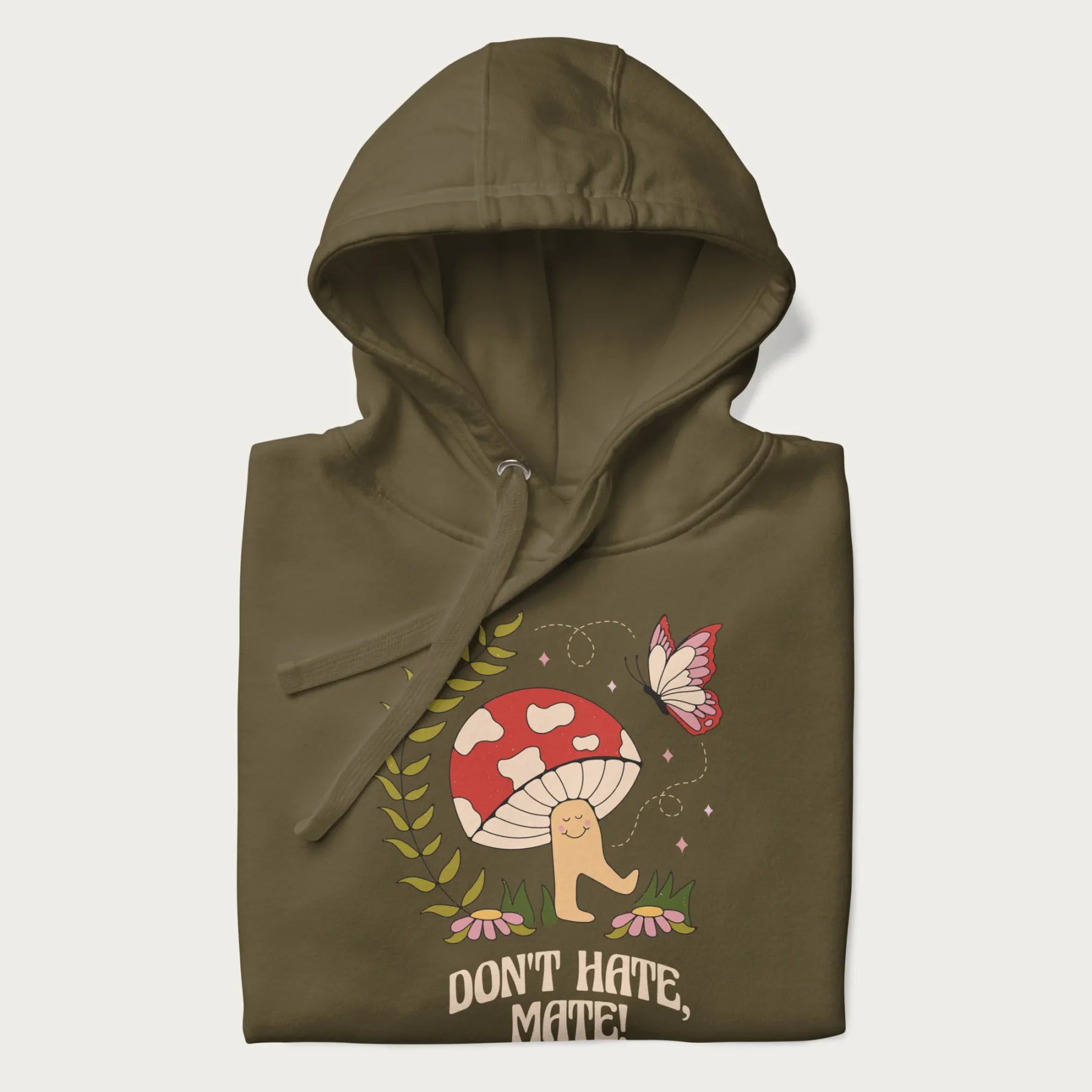 Folded military green hoodie featuring a cute mushroom graphic with the text "Don't Hate, Mate."