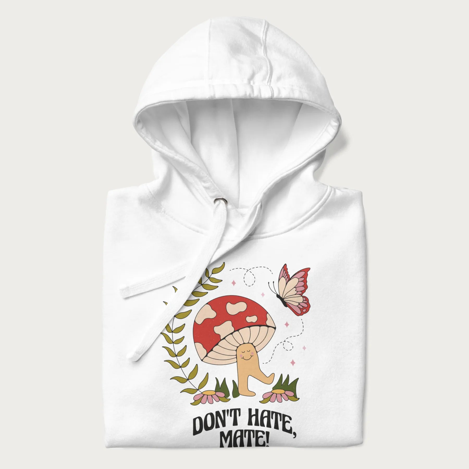 Folded white hoodie featuring a cute mushroom graphic with the text "Don't Hate, Mate."