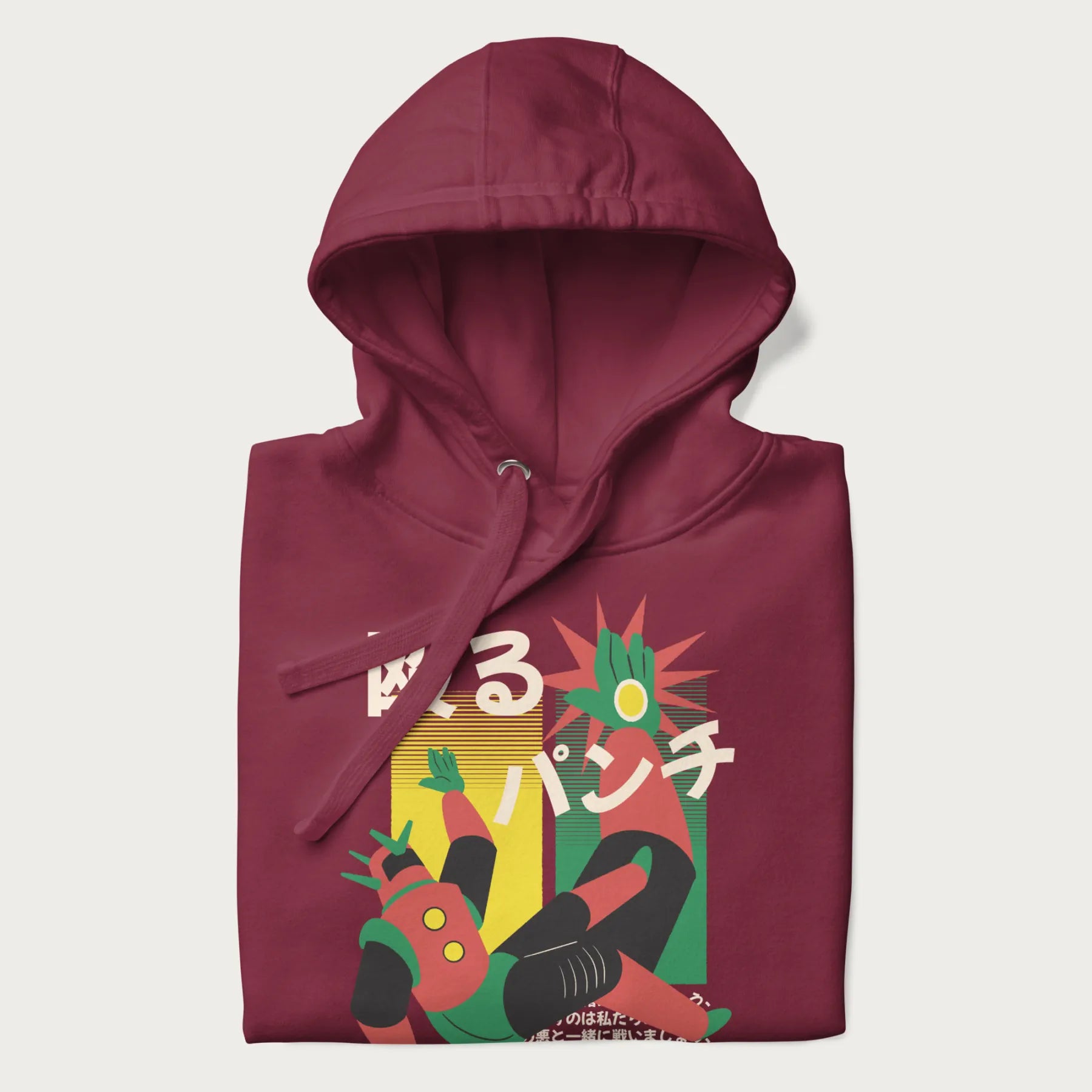 Folded maroon hoodie with Japanese graphic of a mech warrior in mid-battle, highlighted by Japanese text and dynamic retro color palette.