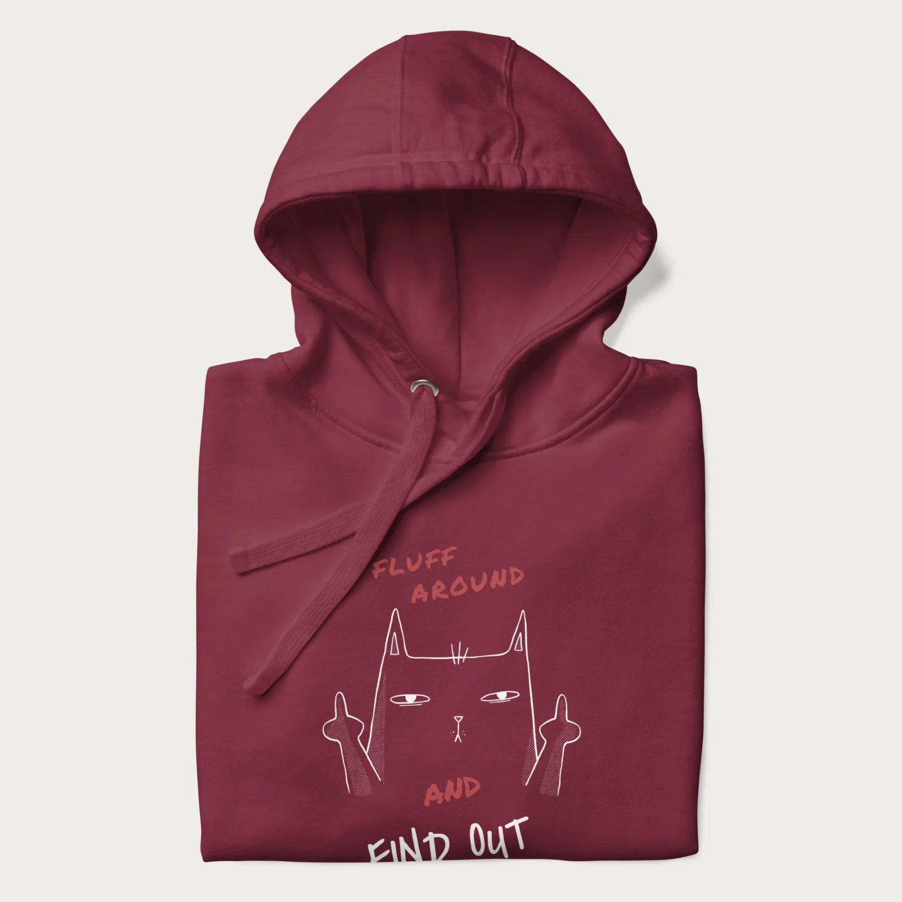 Folded maroon hoodie with a graphic of a cat raising its middle fingers and the text "FLUFF AROUND AND FIND OUT" in red.