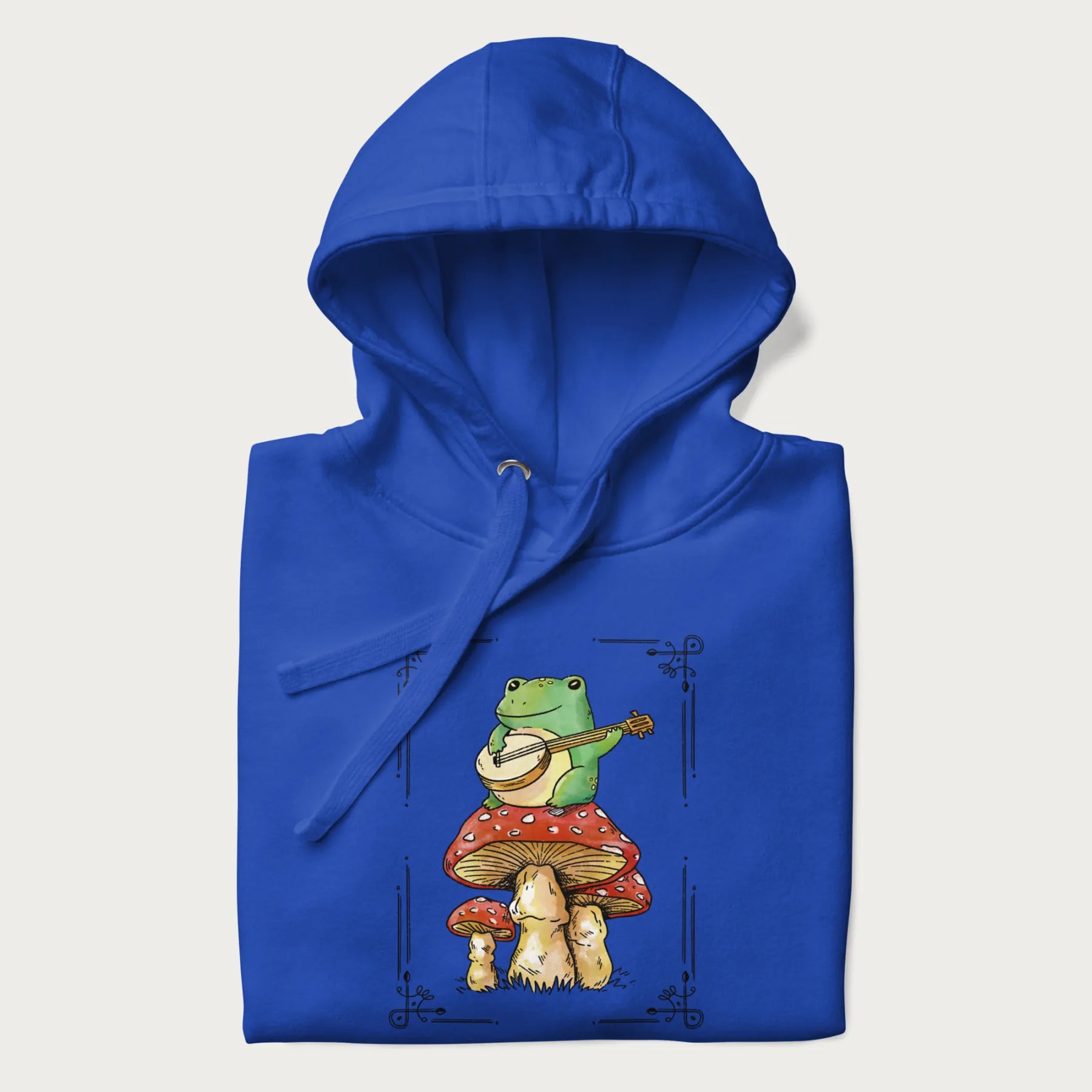 Royal blue hoodie featuring a graphic of a frog playing a banjo on top of red mushrooms.