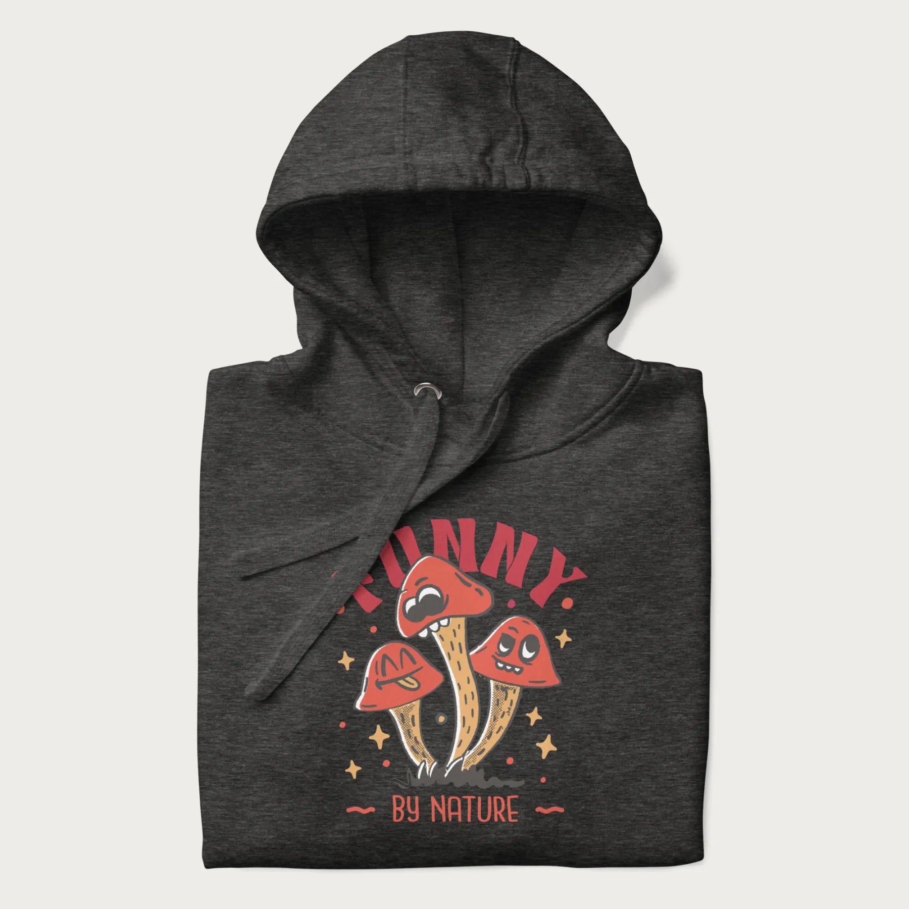 Folded dark grey hoodie featuring a playful graphic of three mushrooms with expressive faces and the text "Funny by Nature."