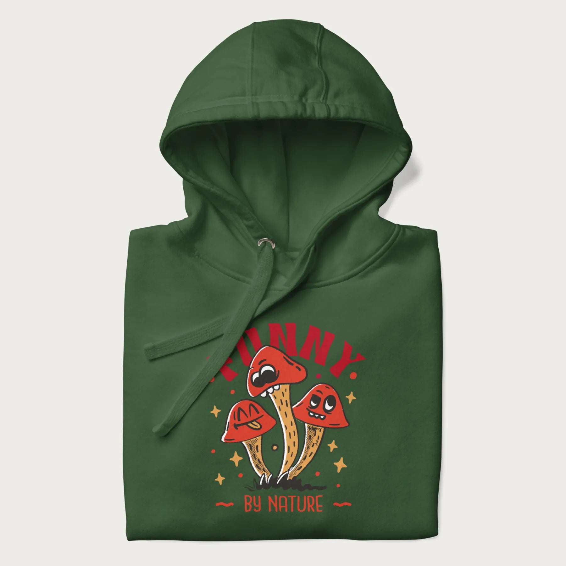 Folded forest green hoodie featuring a playful graphic of three mushrooms with expressive faces and the text "Funny by Nature."