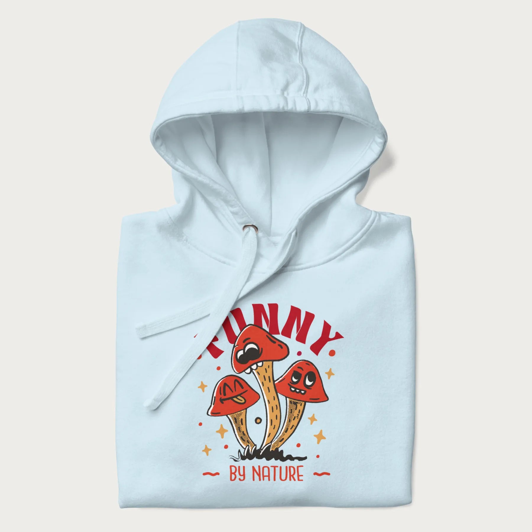 Folded light blue hoodie featuring a playful graphic of three mushrooms with expressive faces and the text "Funny by Nature."