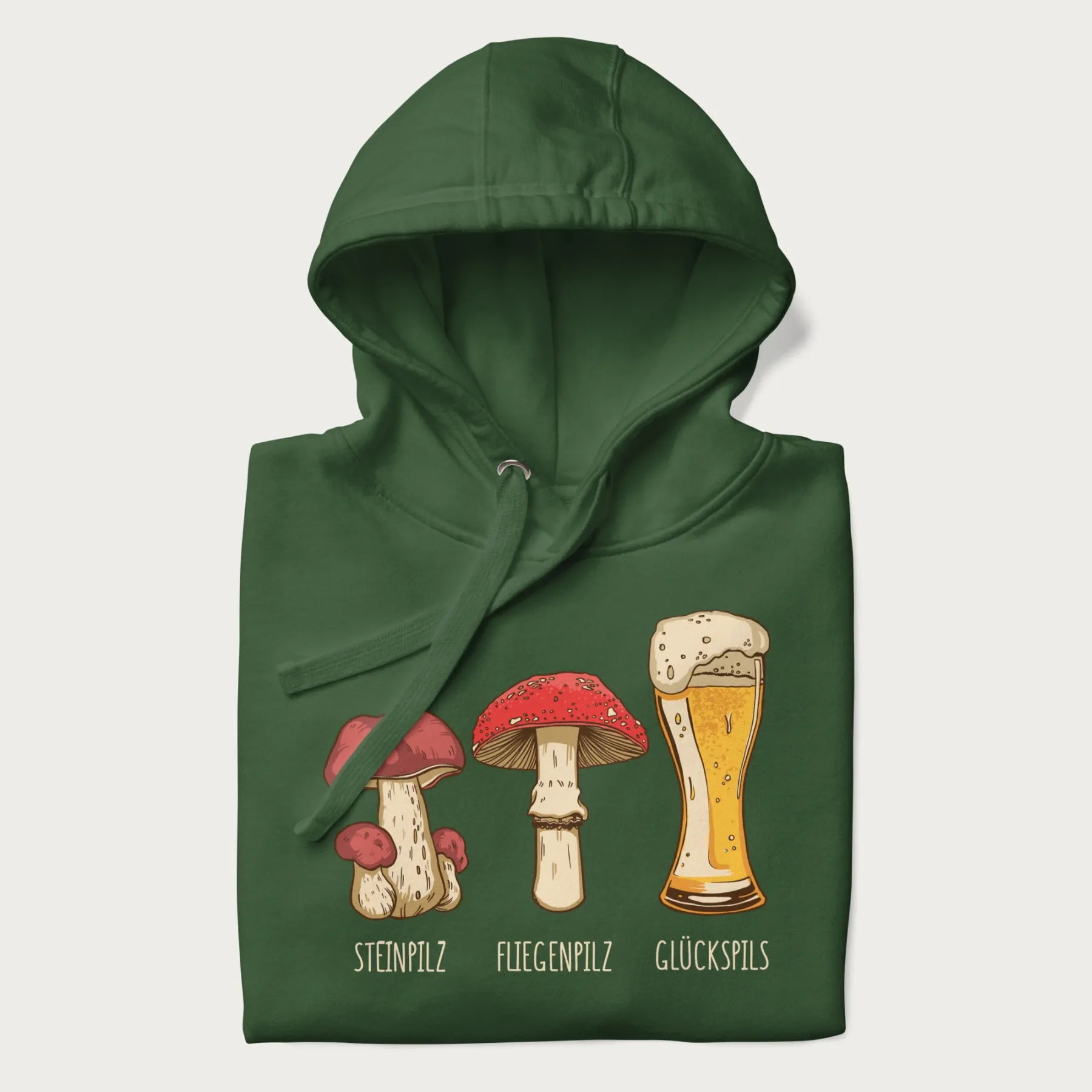 Folded forest green hoodie with illustrations of a Steinpilz, Fliegenpilz, and a beer glass labeled Glückspils.