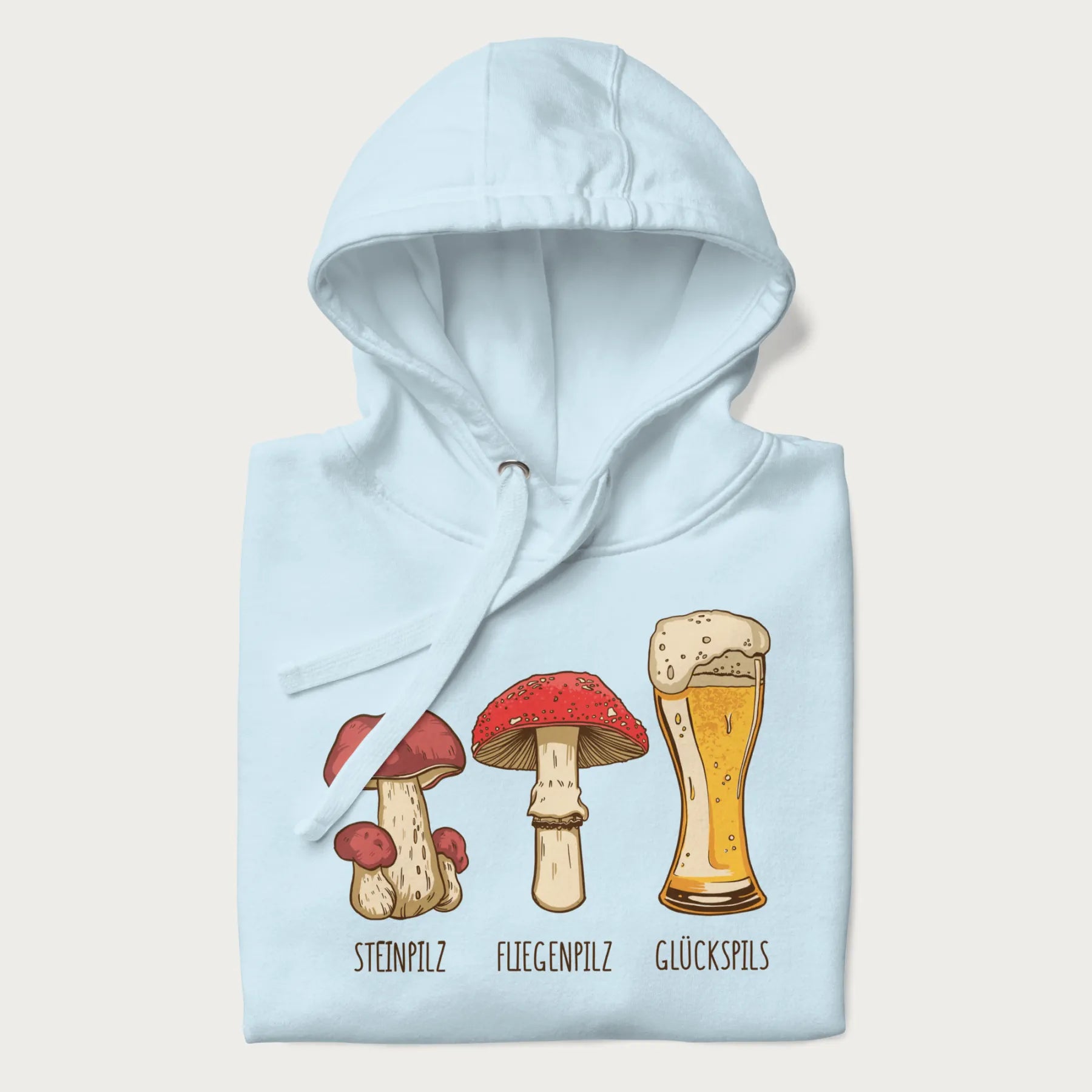 Folded light blue hoodie with illustrations of a Steinpilz, Fliegenpilz, and a beer glass labeled Glückspils.