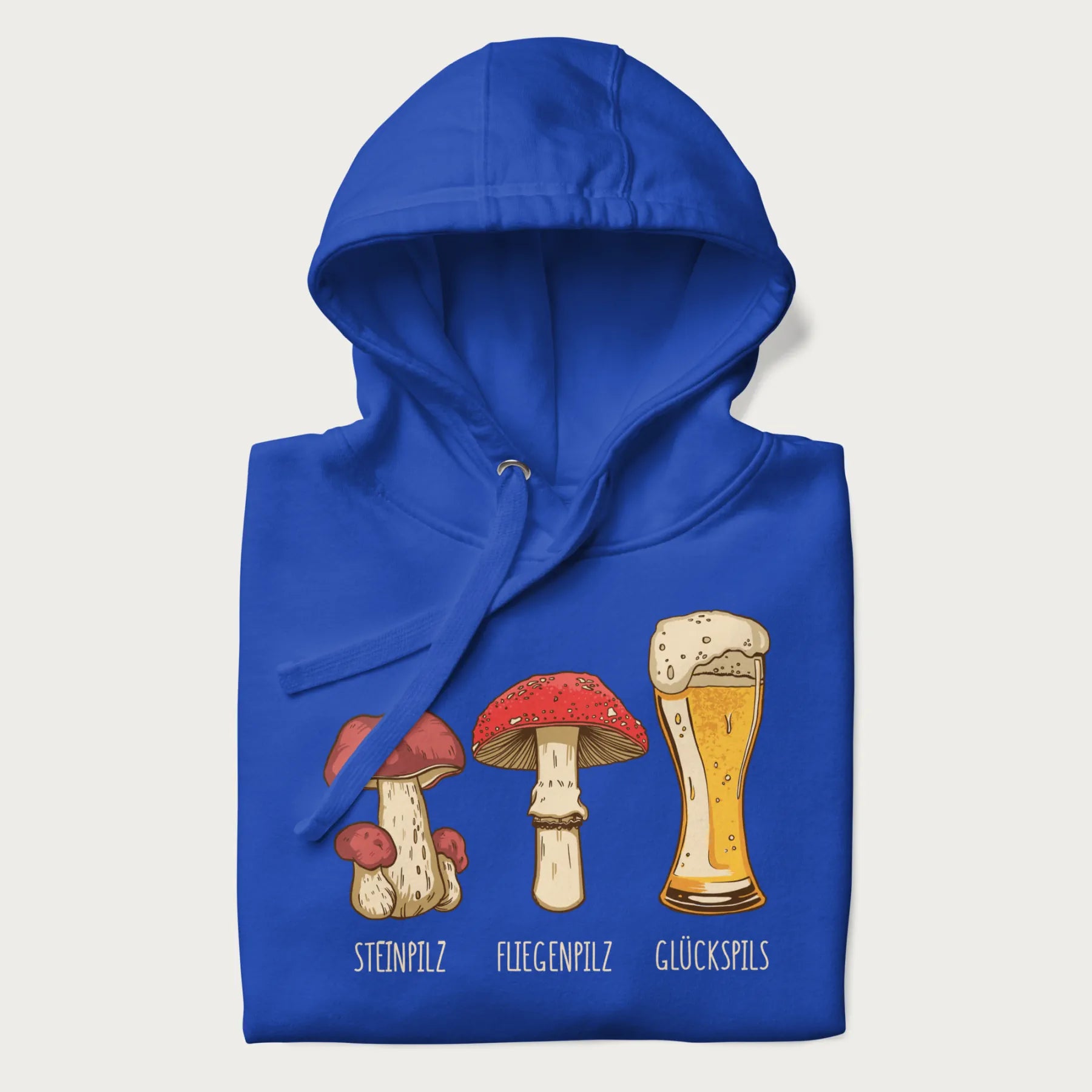 Folded royal blue hoodie with illustrations of a Steinpilz, Fliegenpilz, and a beer glass labeled Glückspils.