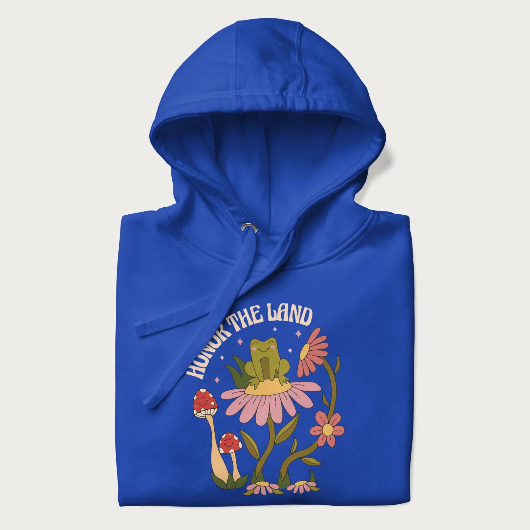 Folded royal blue hoodie with a graphic of a frog sitting on a flower, surrounded by mushrooms and flowers, with the text 'Honor the Land'.