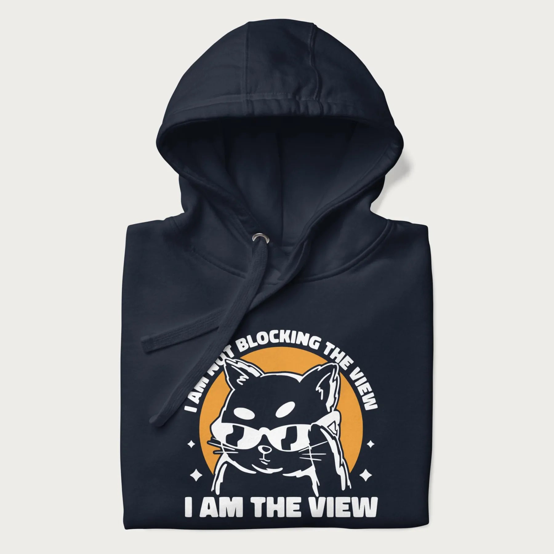 Folded navy blue hoodie with a confident cat wearing sunglasses and the phrase 'I am not blocking the view, I am the view'.