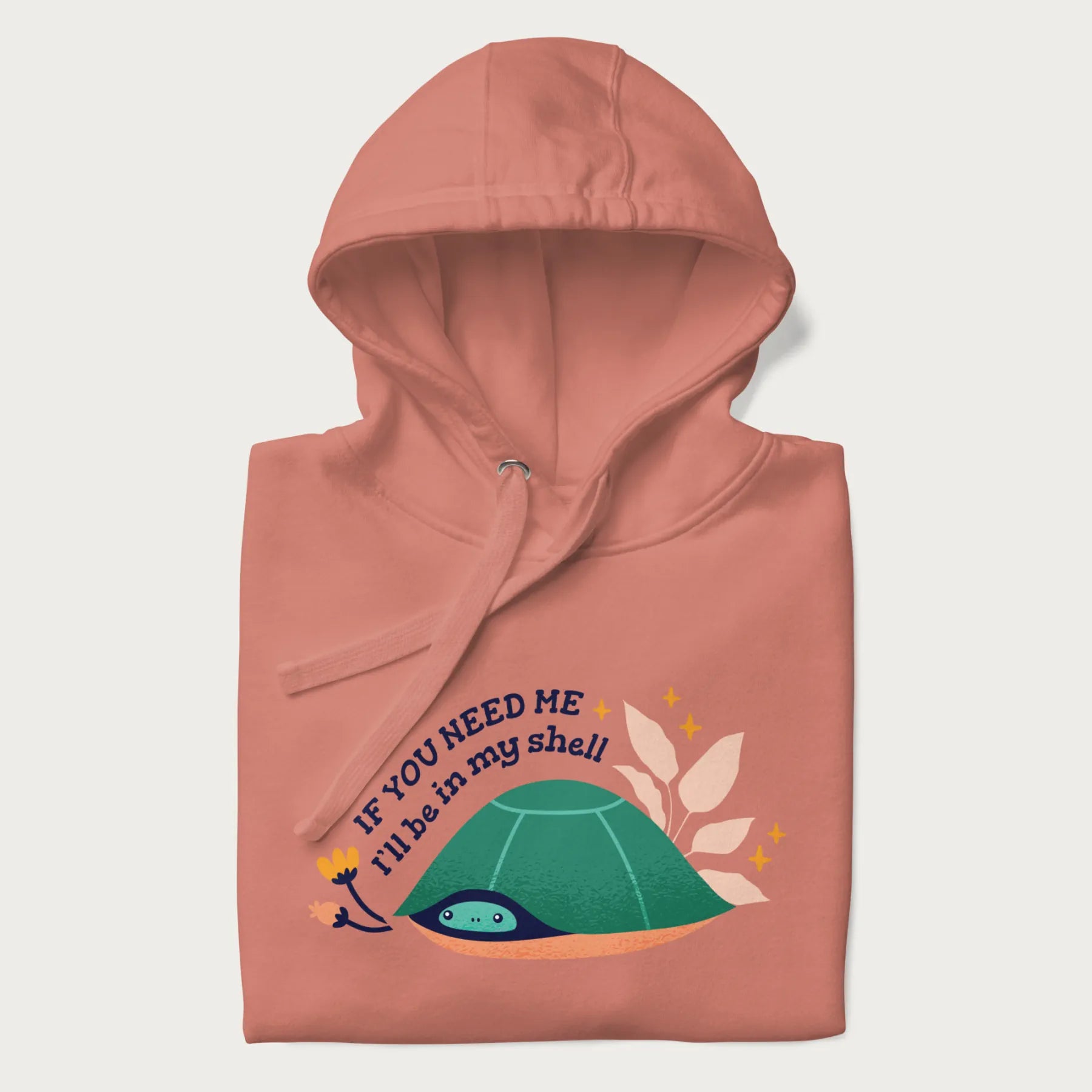 Folded light pink hoodie with a graphic of a turtle peeking out from its shell and the text 'If You Need Me I'll be in my shell'.