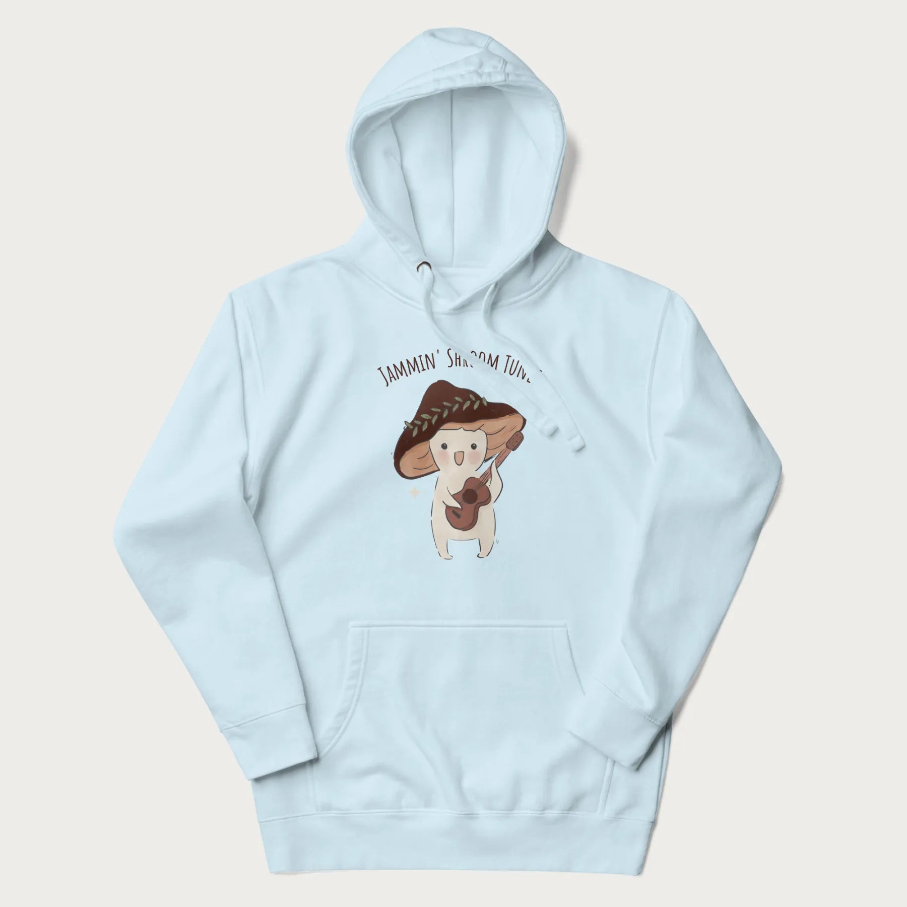 Light blue hoodie with a cute cottagecore mushroom character playing a guitar and the pun 'Jammin' Shroom Tunes' above.