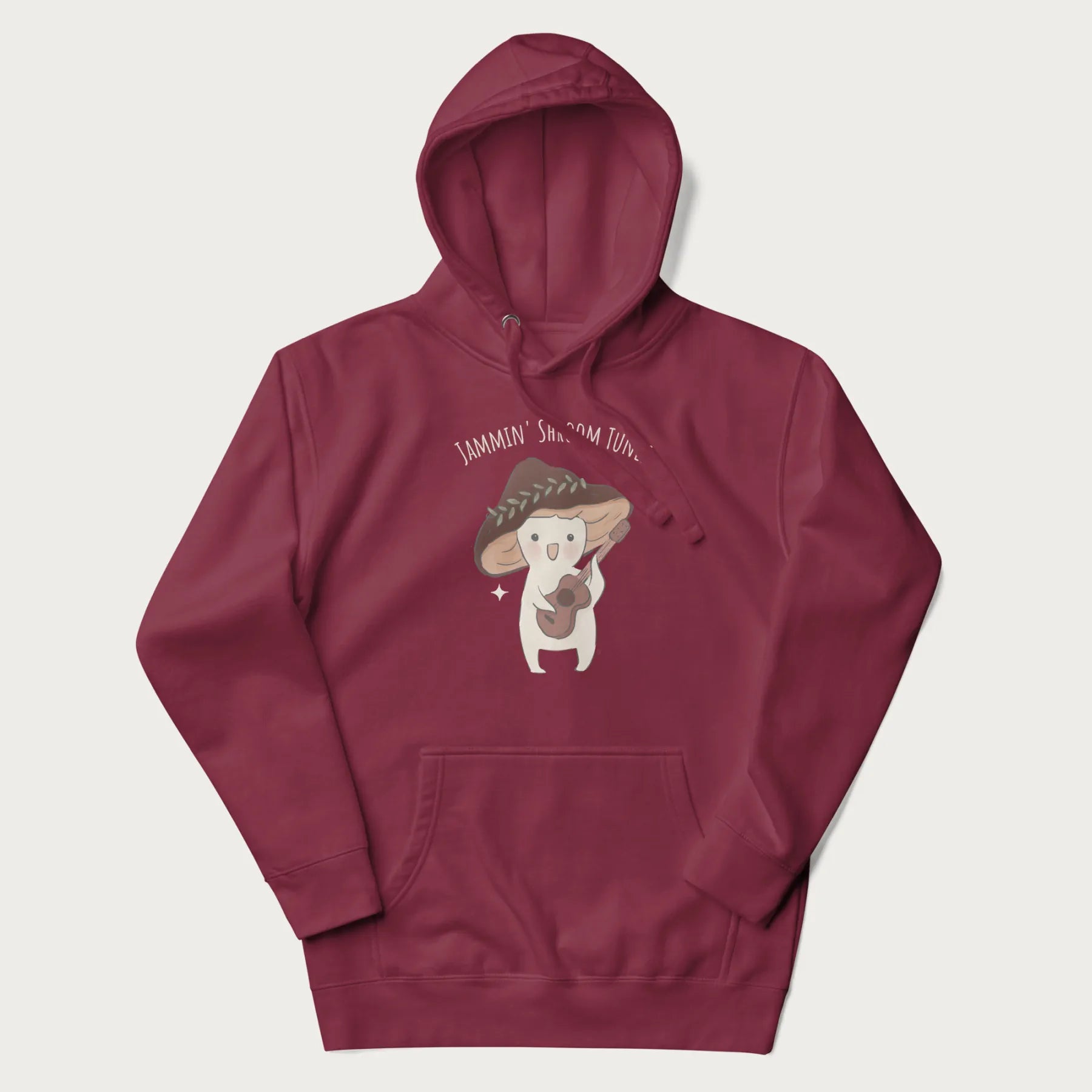 Maroon hoodie with a cute cottagecore mushroom character playing a guitar and the pun 'Jammin' Shroom Tunes' above.