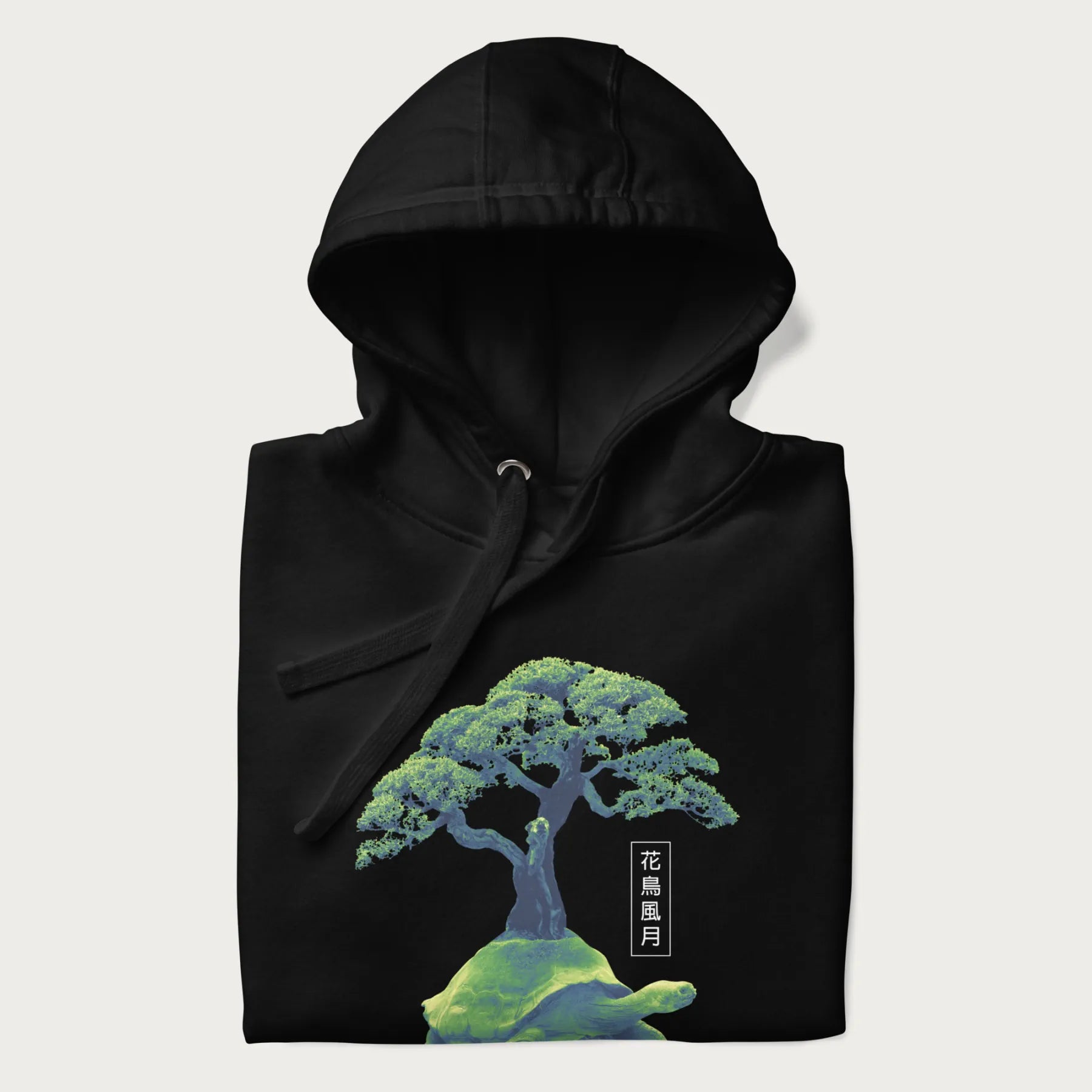 Folded black hoodie with a vibrant graphic of a turtle carrying a bonsai tree and Japanese text '花鳥風月.'