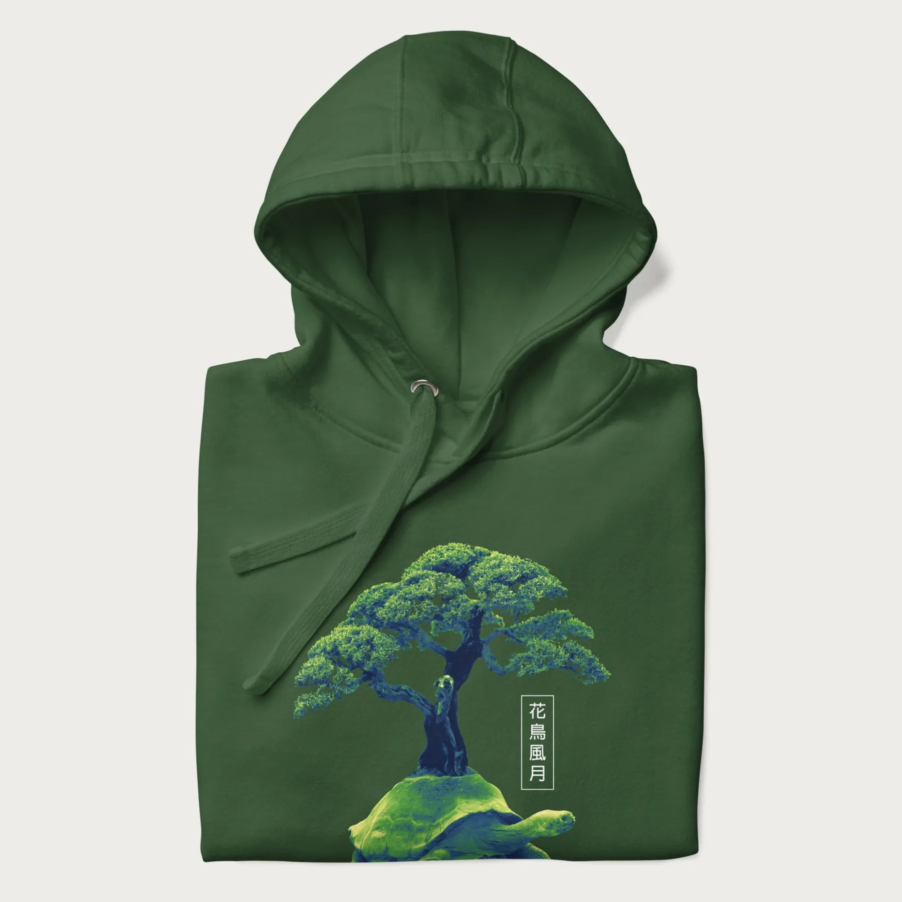 Folded forest green hoodie with a vibrant graphic of a turtle carrying a bonsai tree and Japanese text '花鳥風月.'