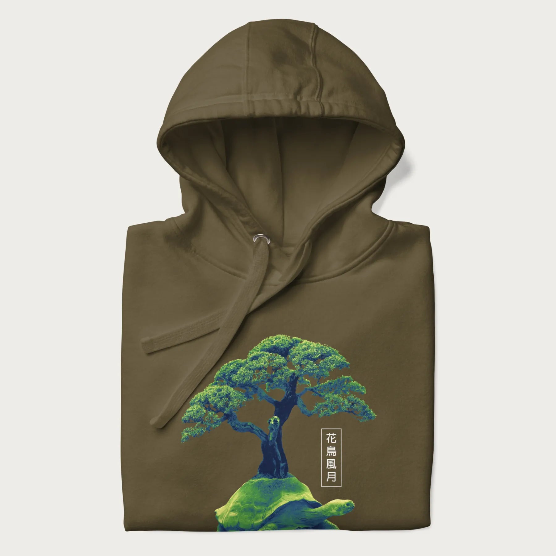 Folded military green hoodie with a vibrant graphic of a turtle carrying a bonsai tree and Japanese text '花鳥風月.'