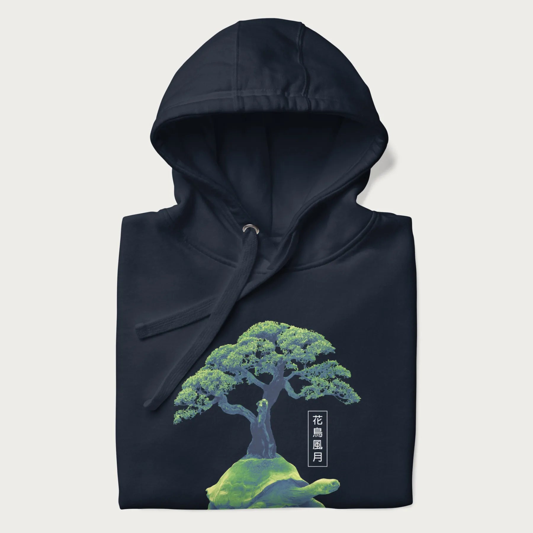 Folded navy blue hoodie with a vibrant graphic of a turtle carrying a bonsai tree and Japanese text '花鳥風月.'