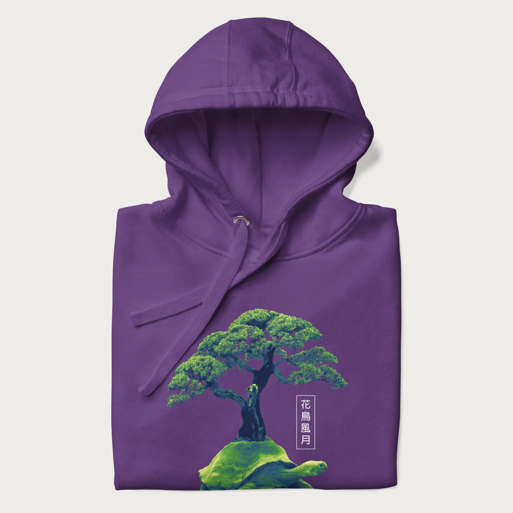 Folded purple hoodie with a vibrant graphic of a turtle carrying a bonsai tree and Japanese text '花鳥風月.'