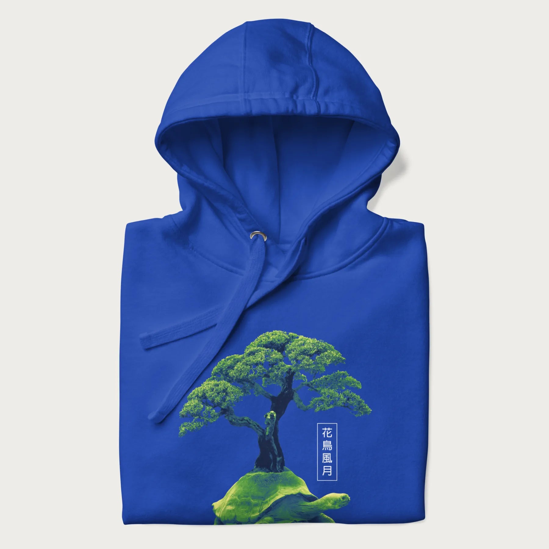 Folded royal blue hoodie with a vibrant graphic of a turtle carrying a bonsai tree and Japanese text '花鳥風月.'