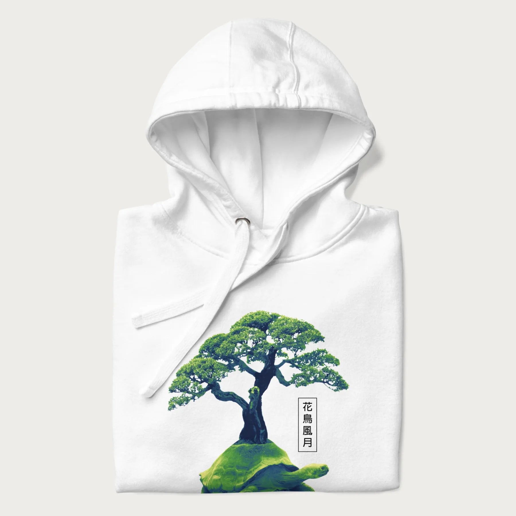 Folded white hoodie with a vibrant graphic of a turtle carrying a bonsai tree and Japanese text '花鳥風月.'