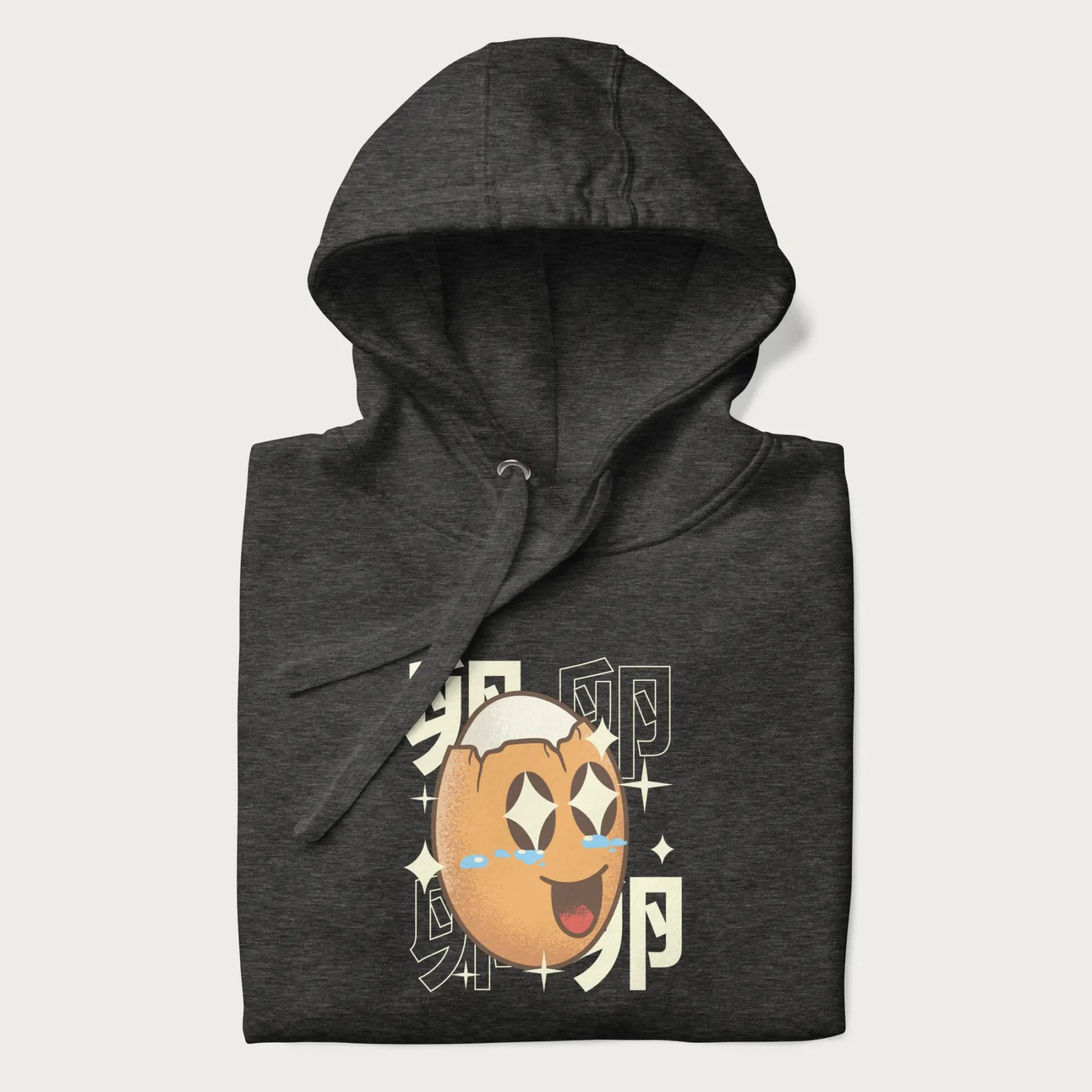 Folded dark grey hoodie with Japanese graphic of a smiling egg with tears of joy, surrounded by the Japanese text '卵' (Egg).
