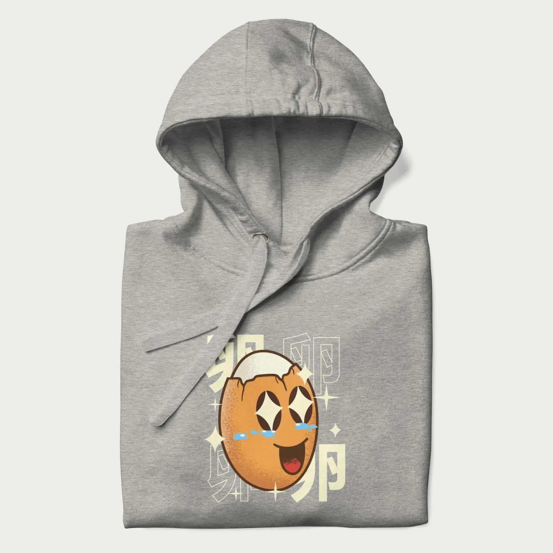Folded light grey hoodie with Japanese graphic of a smiling egg with tears of joy, surrounded by the Japanese text '卵' (Egg).
