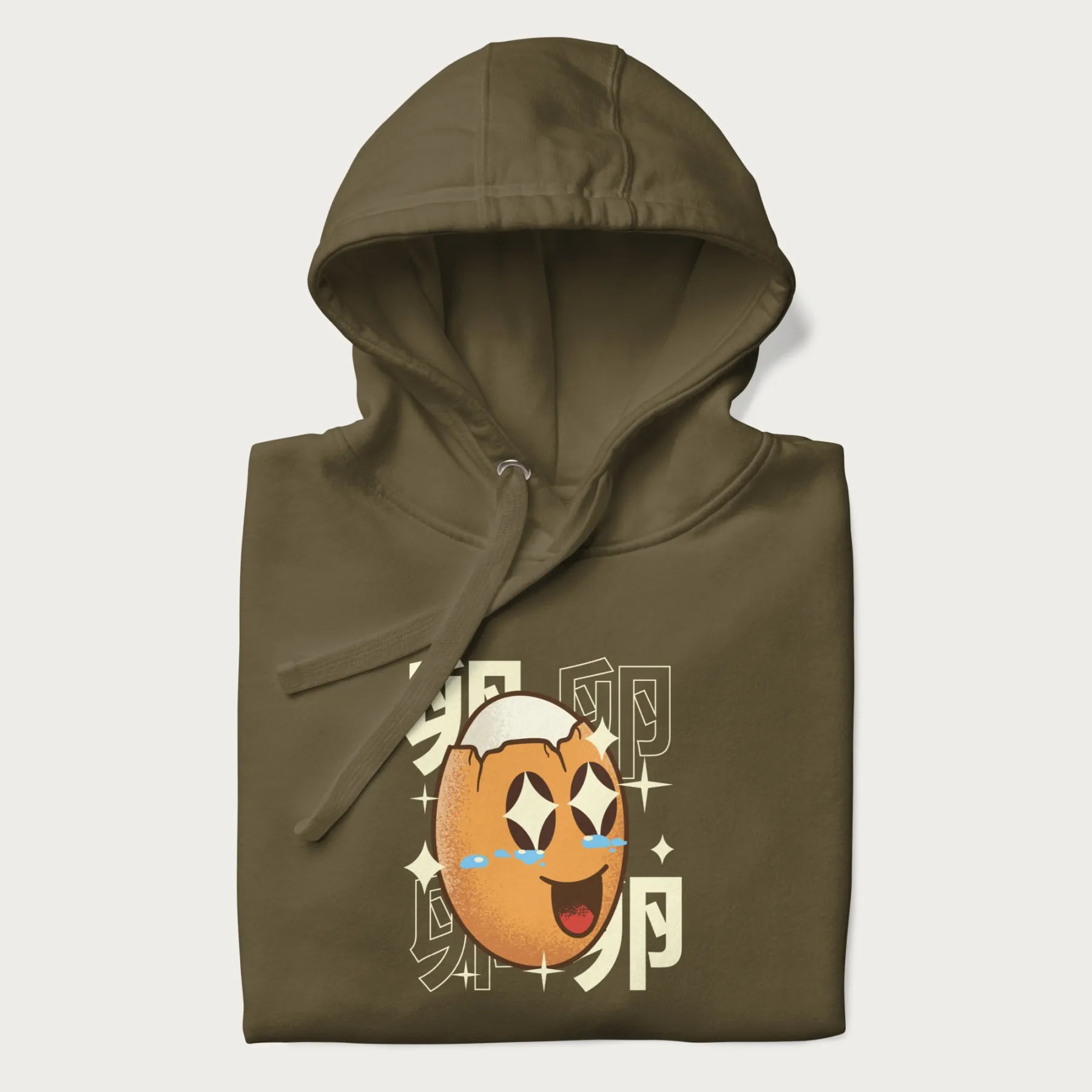 Folded military green hoodie with Japanese graphic of a smiling egg with tears of joy, surrounded by the Japanese text '卵' (Egg).