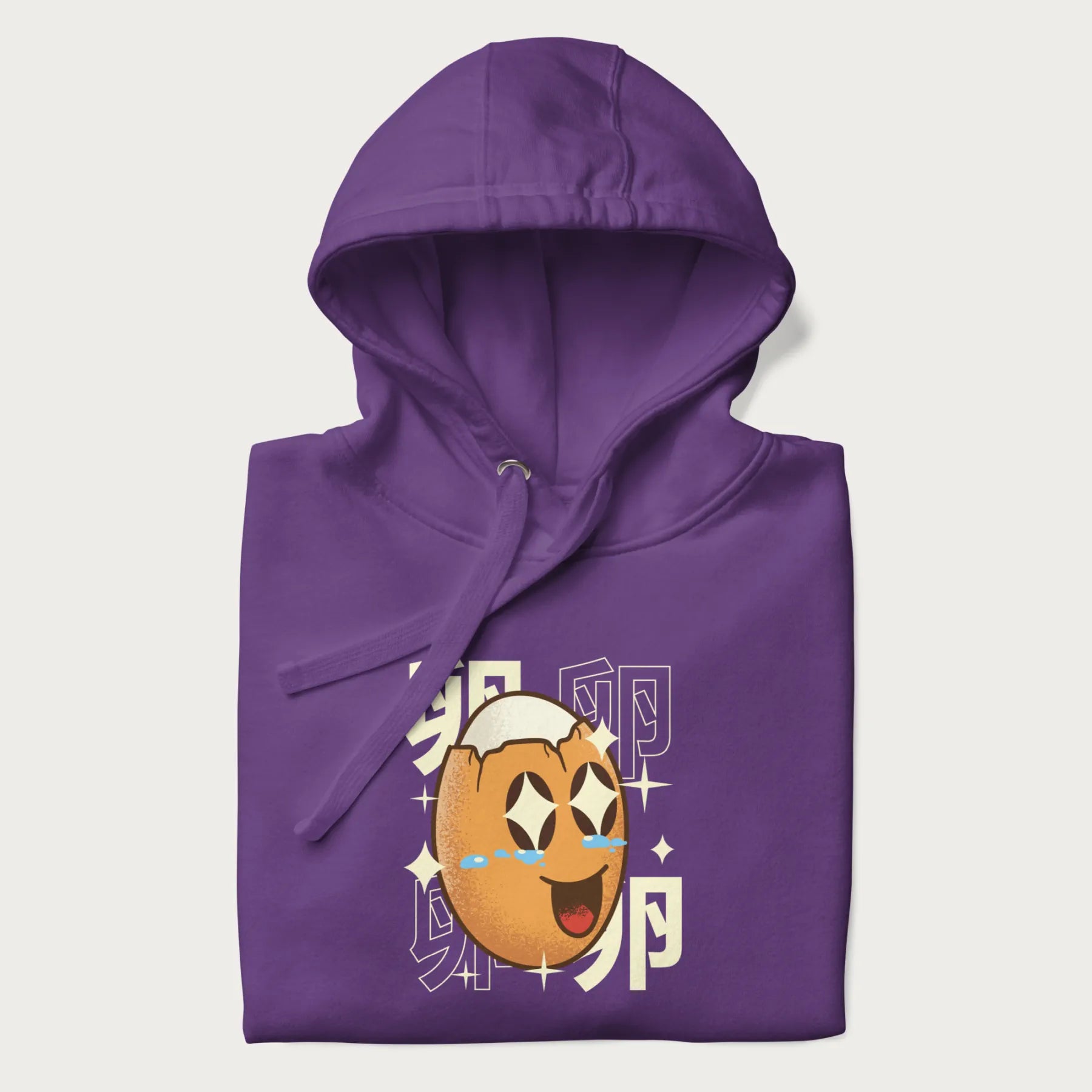Folded purple hoodie with Japanese graphic of a smiling egg with tears of joy, surrounded by the Japanese text '卵' (Egg).