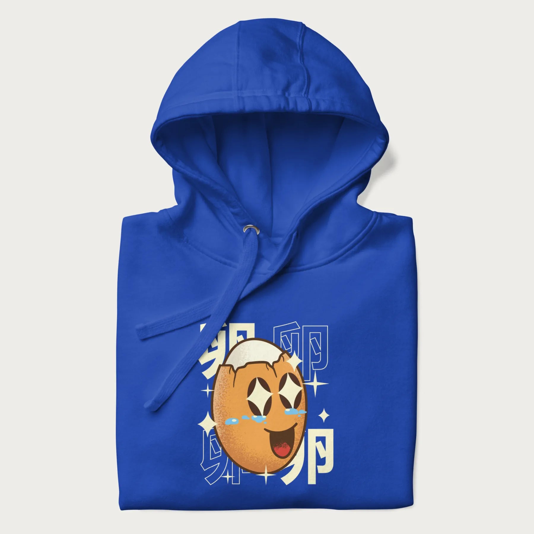 Folded royal blue hoodie with Japanese graphic of a smiling egg with tears of joy, surrounded by the Japanese text '卵' (Egg).
