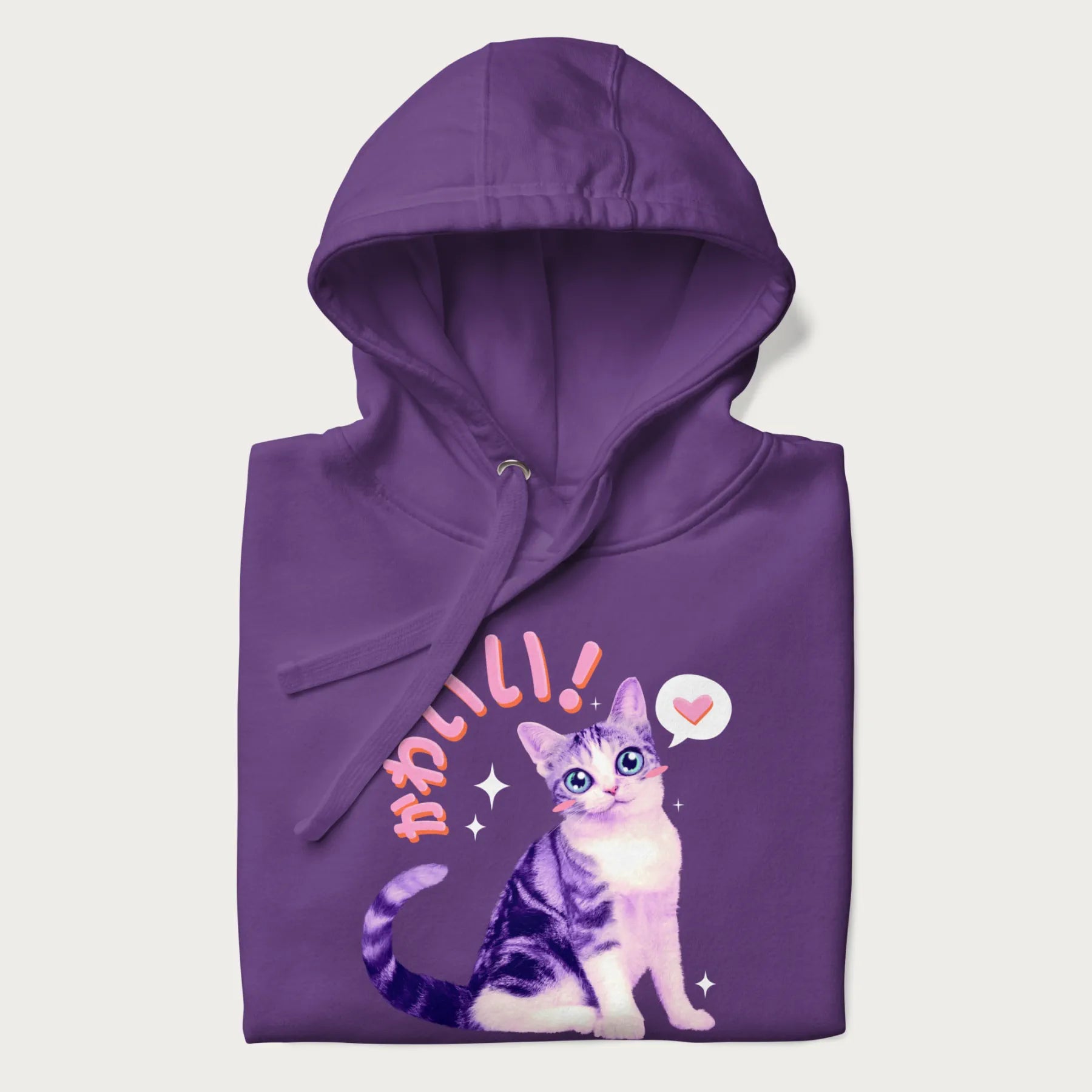 Folded purple hoodie with a graphic of a blue-eyed kitten and Japanese kawaii-style lettering, stars, and a heart.