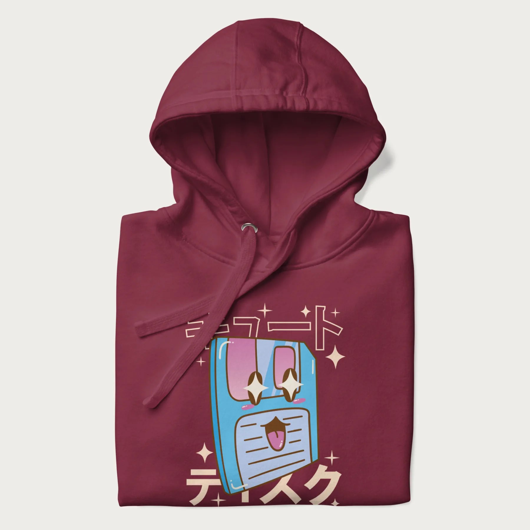 Folded maroon hoodie with Japanese graphic of a cute sky-blue floppy disk with Japanese text 'キュート' (Cute) and 'ティスク' (Disk).