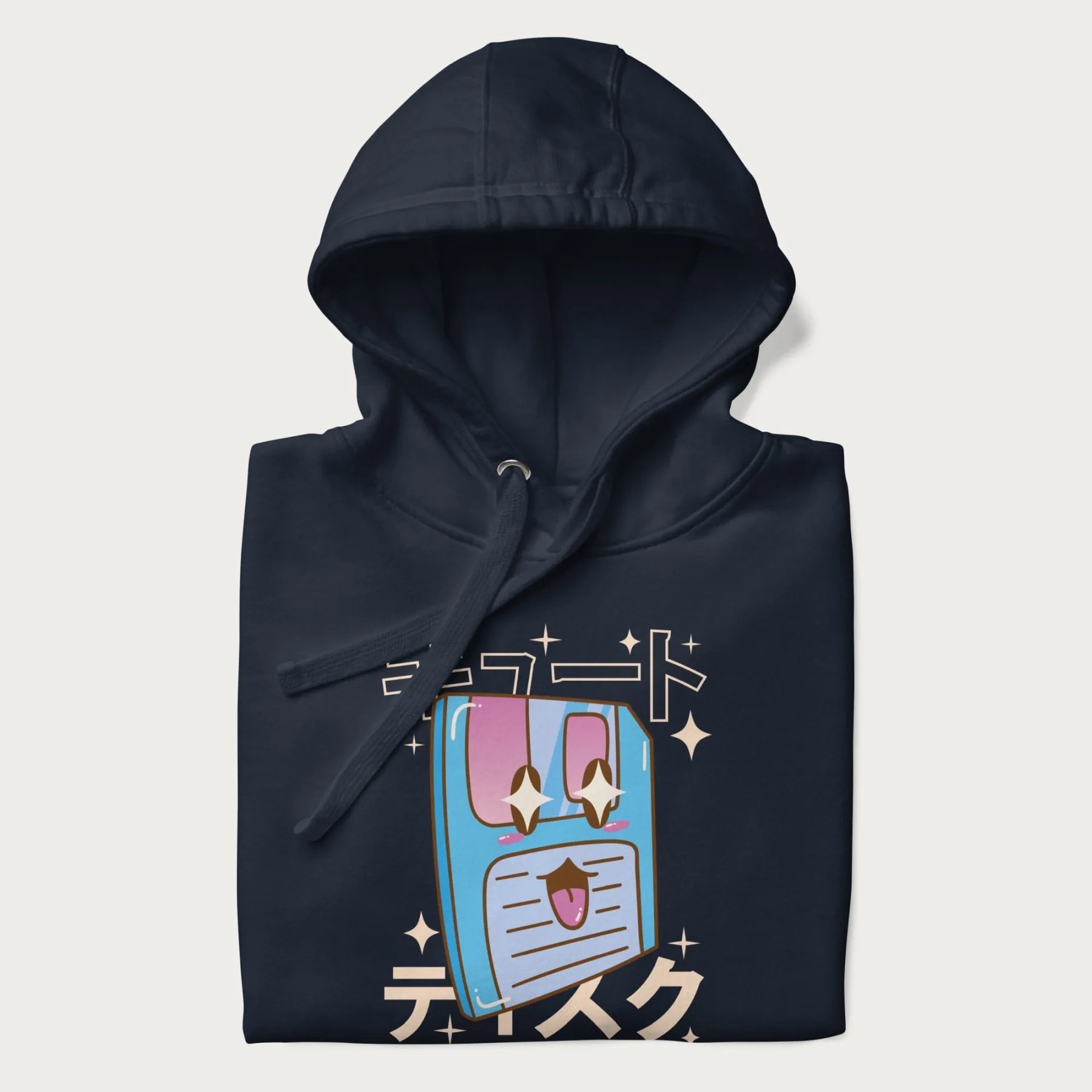 Folded navy blue hoodie with Japanese graphic of a cute sky-blue floppy disk with Japanese text 'キュート' (Cute) and 'ティスク' (Disk).